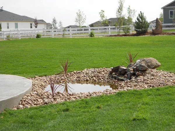 Water feature with pond moss rock boulders and river rock and decorative grasses