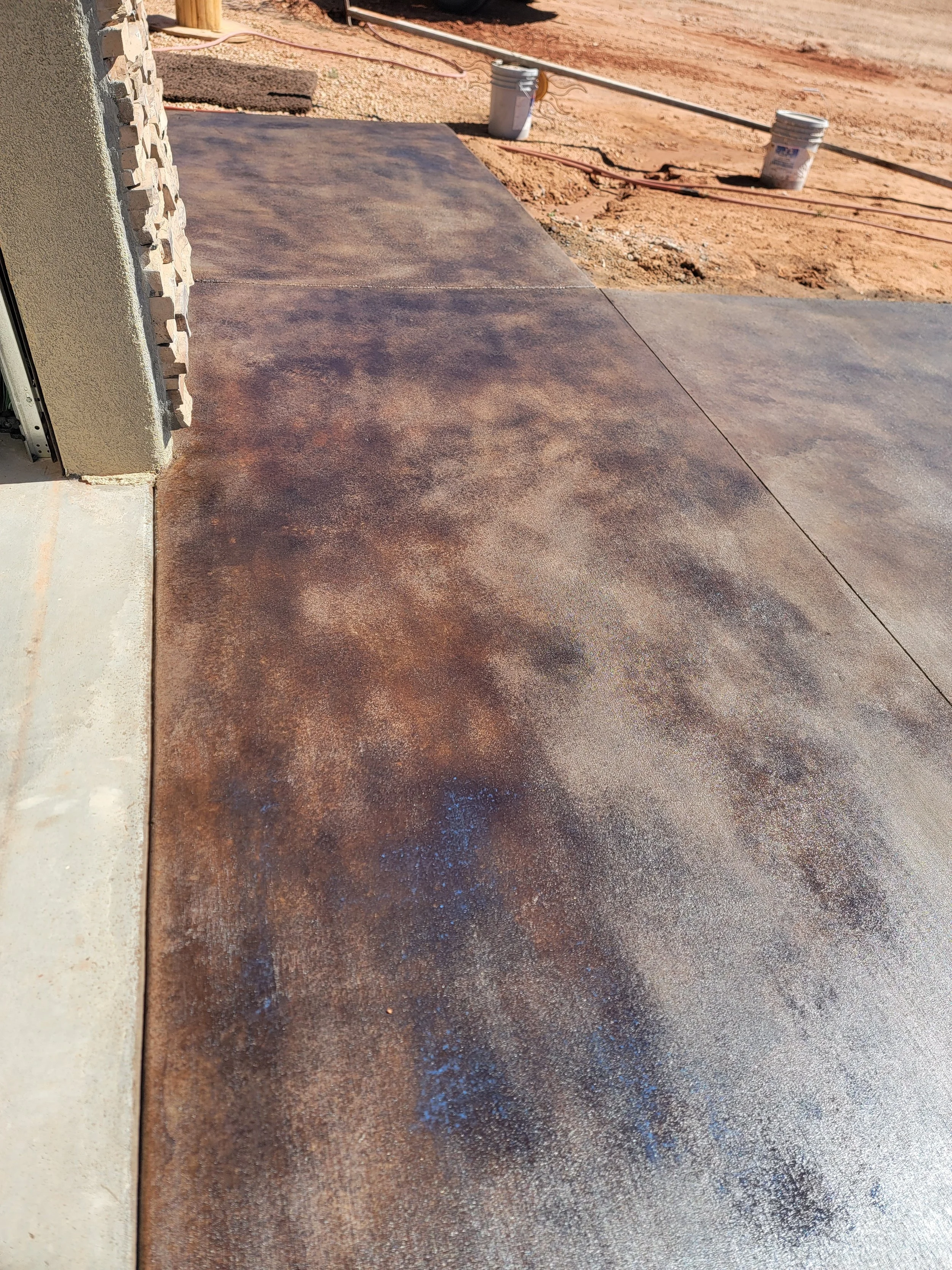 Newly poured concrete walkway outside a building, with surrounding construction area and soil.