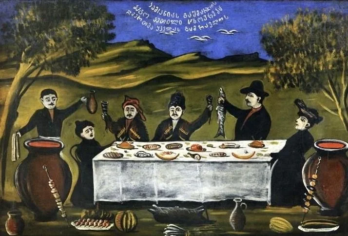 A painting of six men sitting at a long table outdoors, with food and drinks, surrounded by trees and hills in the background. Some men are holding fish, and there are large jars on either side of the scene.