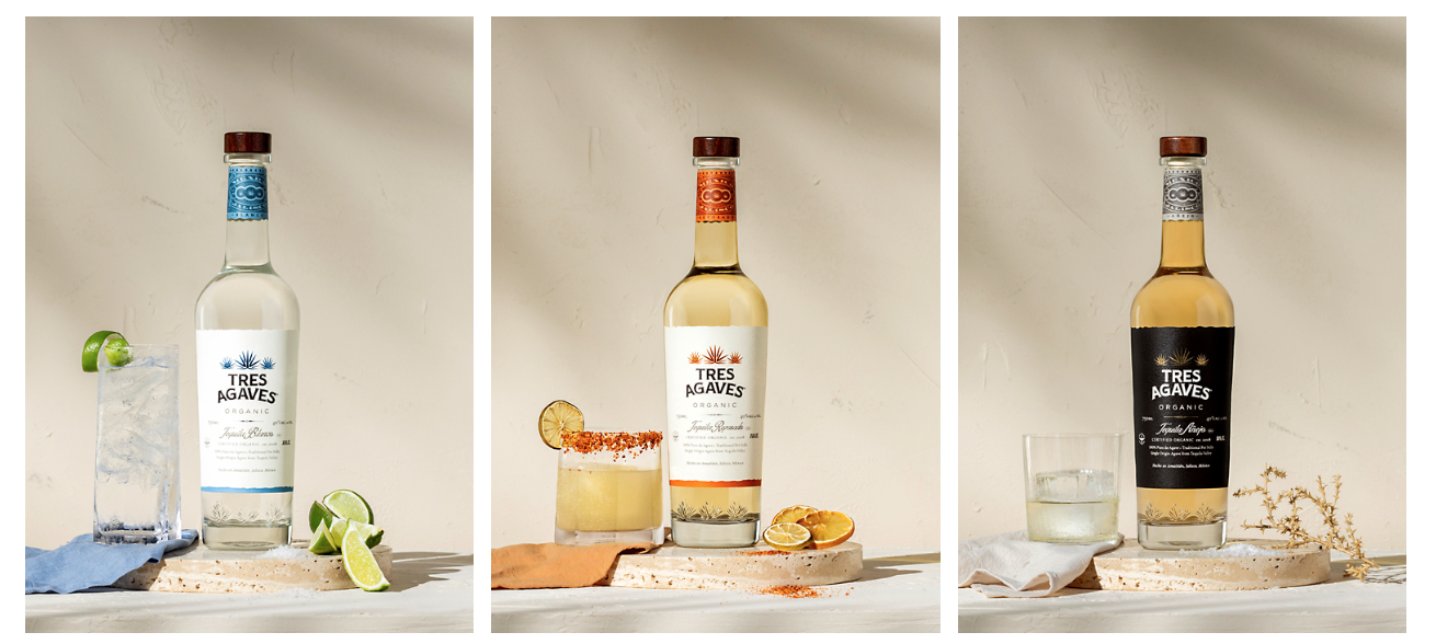 Three bottles of Tres Agaves organic tequila with different cocktails and garnishes against a neutral background.