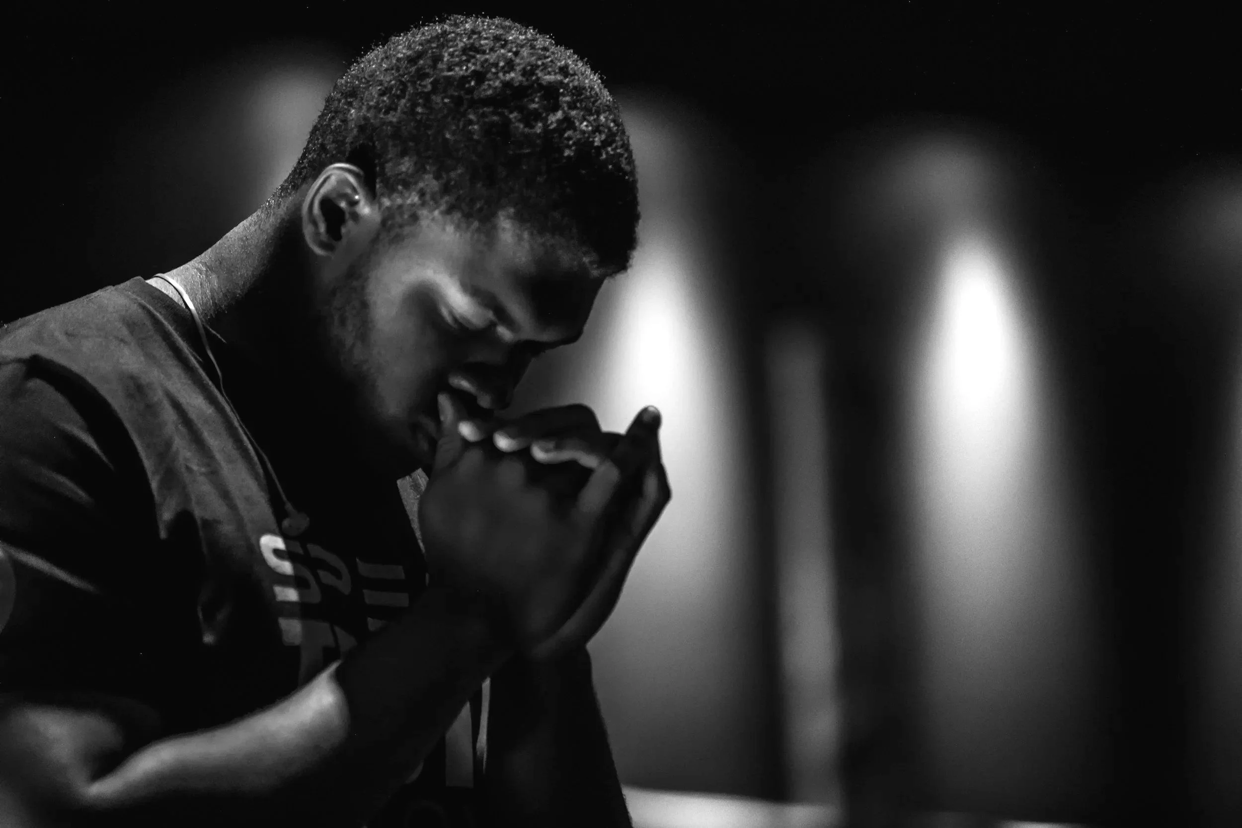Young man praying in worship and reflection representing faith, prayer, and spiritual growth at First Zion Missionary Baptist Church.