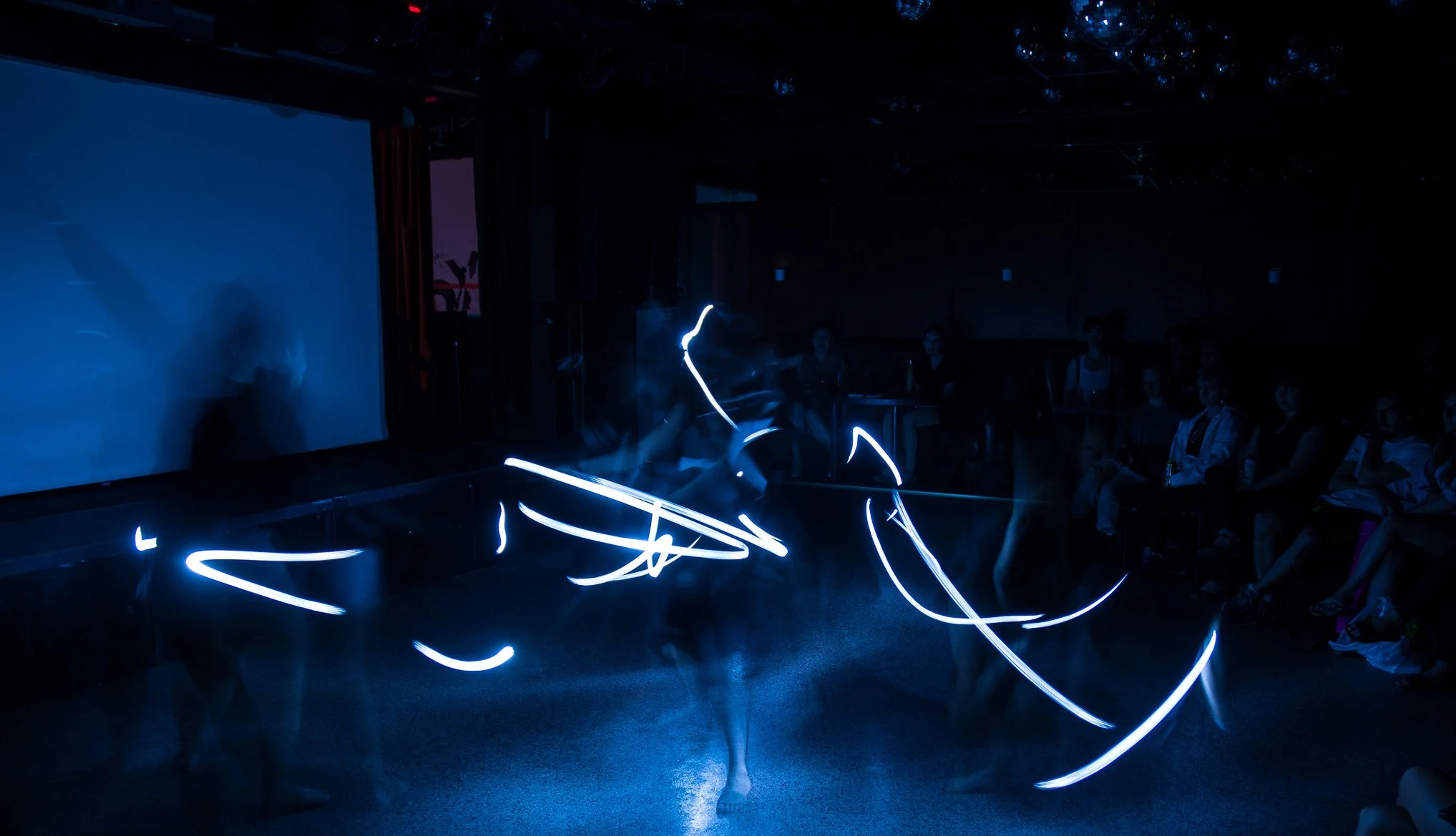 dancers in the dark with lights showing movement