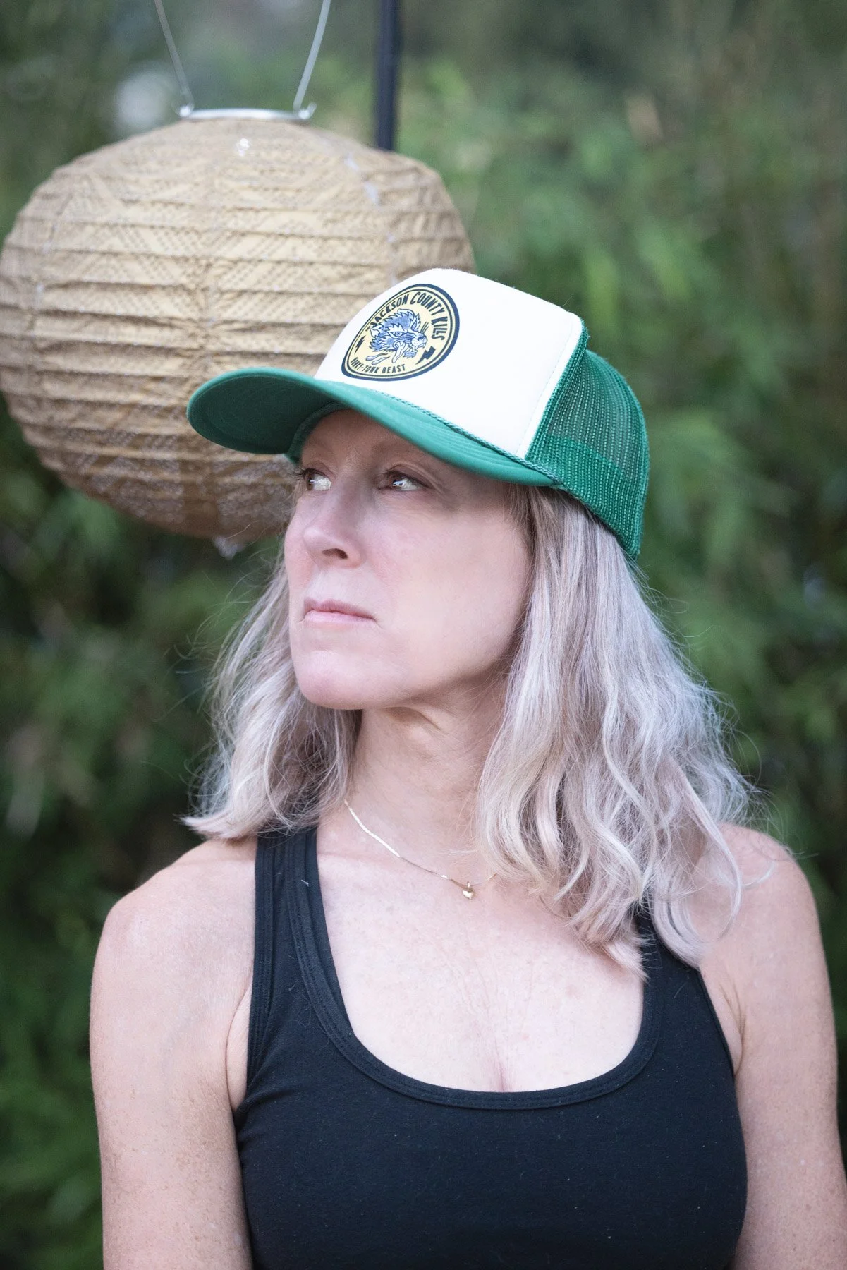 Teacher Shannon in a black tank and trucker hat looking left off the screen