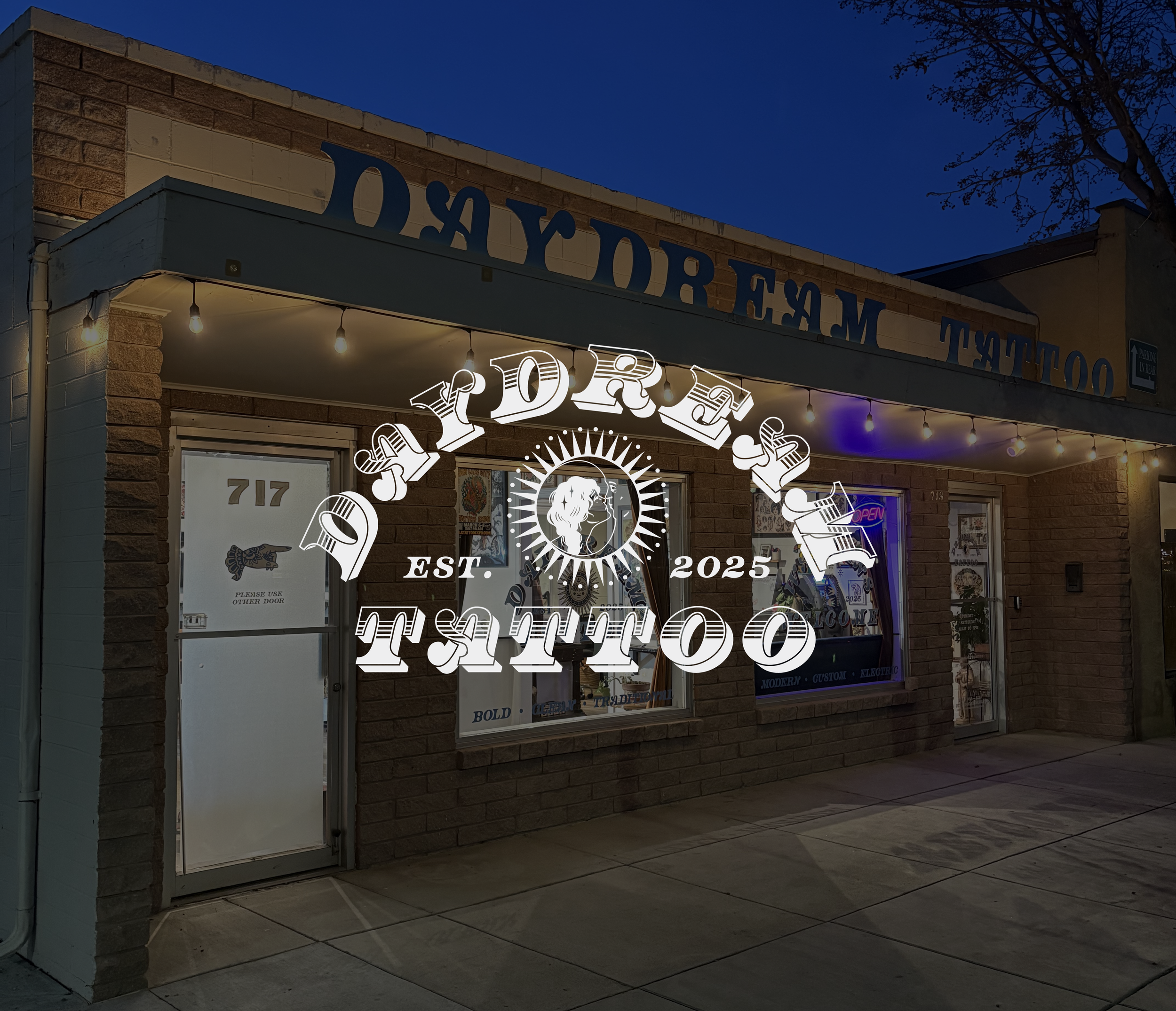 Storefront with brick walls, illuminated string lights, and signage with stylized text. Daydream logo placed center on the image.
