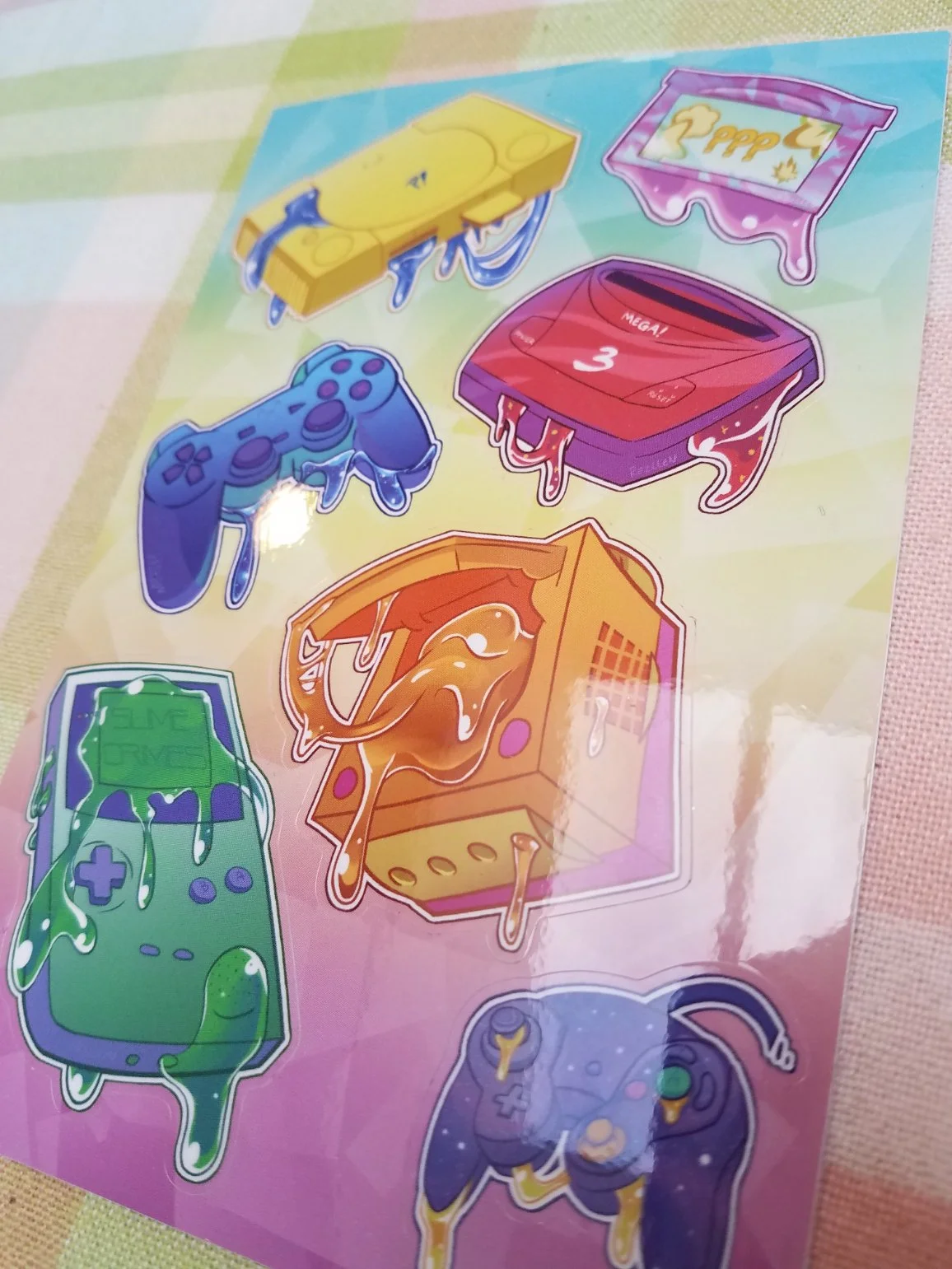 Colorful stickers of various gaming consoles, controllers, and gaming-related objects with cartoonish, melting appearances.