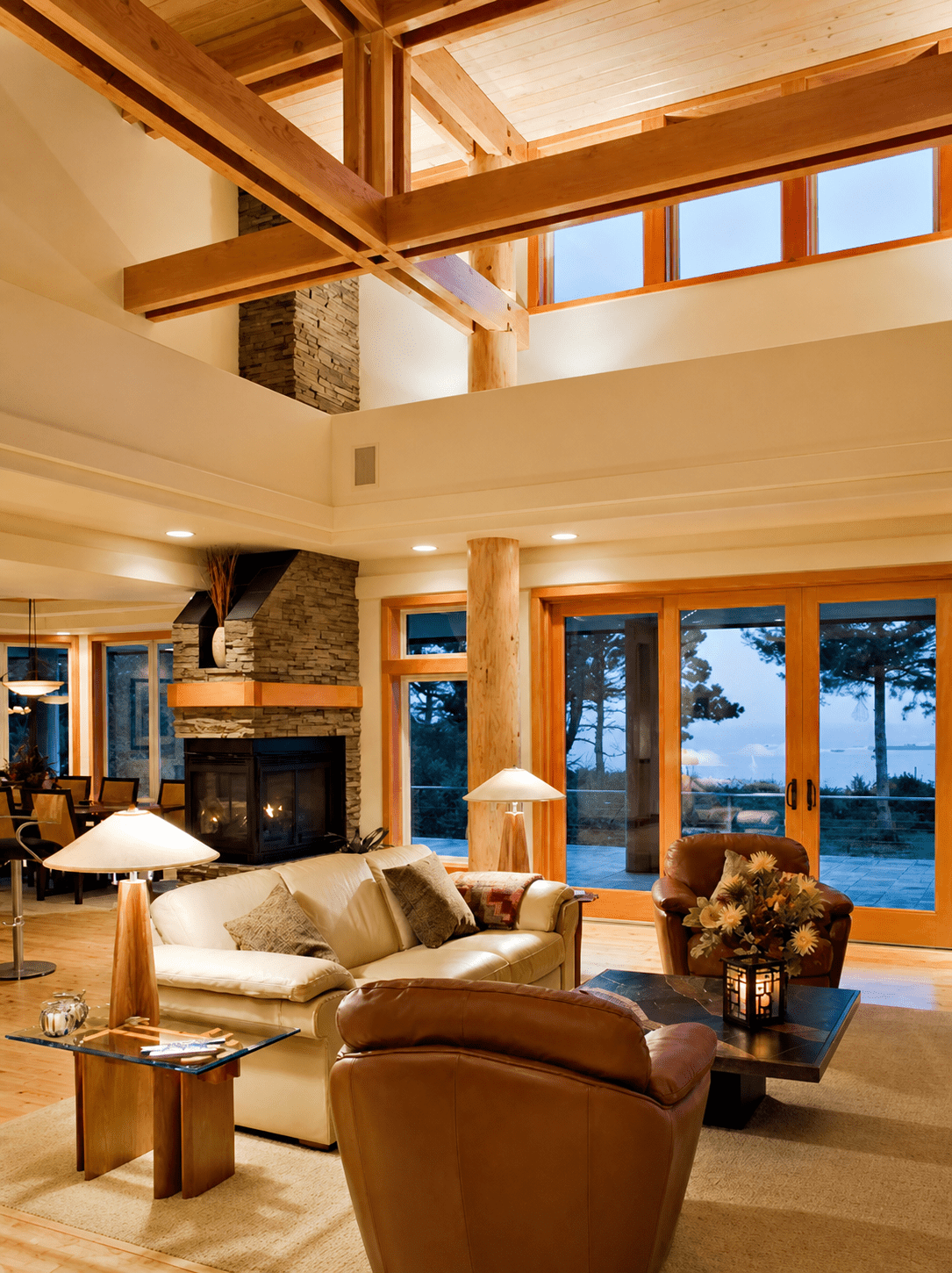 Great room with Douglas fir timber beams, stacked stone fireplace, and Pacific Ocean views