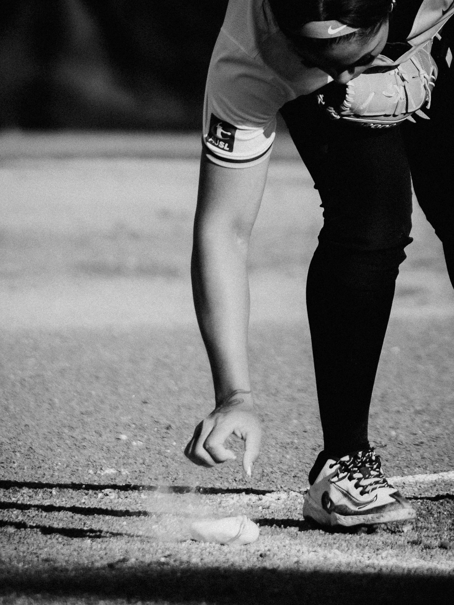 A person in athletic shoes and sporting clothing is on a track, bent forward with one foot at the starting line, preparing to race.