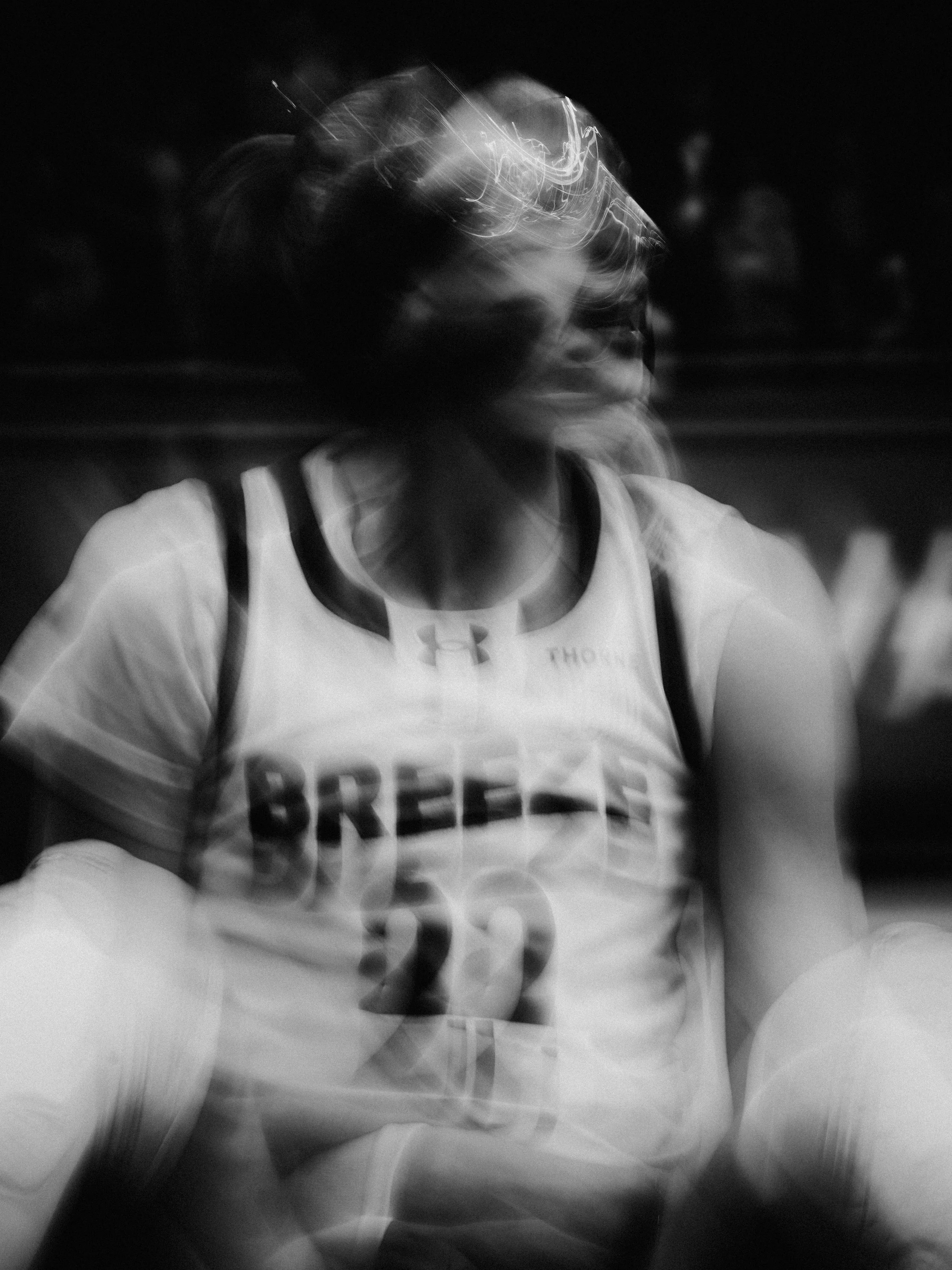 A person wearing a white sports shirt, backpack, and sunglasses appears to be moving quickly, creating a blurred motion effect in the photo.