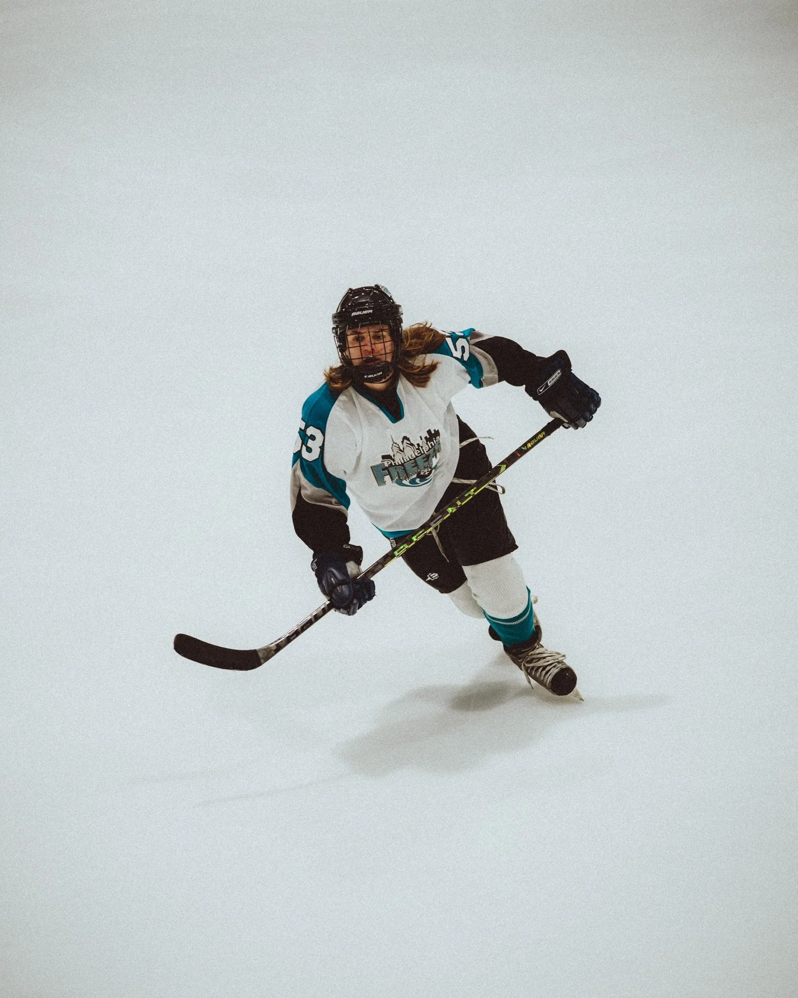 A woman in hockey gear skating on ice, wearing a helmet, gloves, and a jersey with the number 73.
