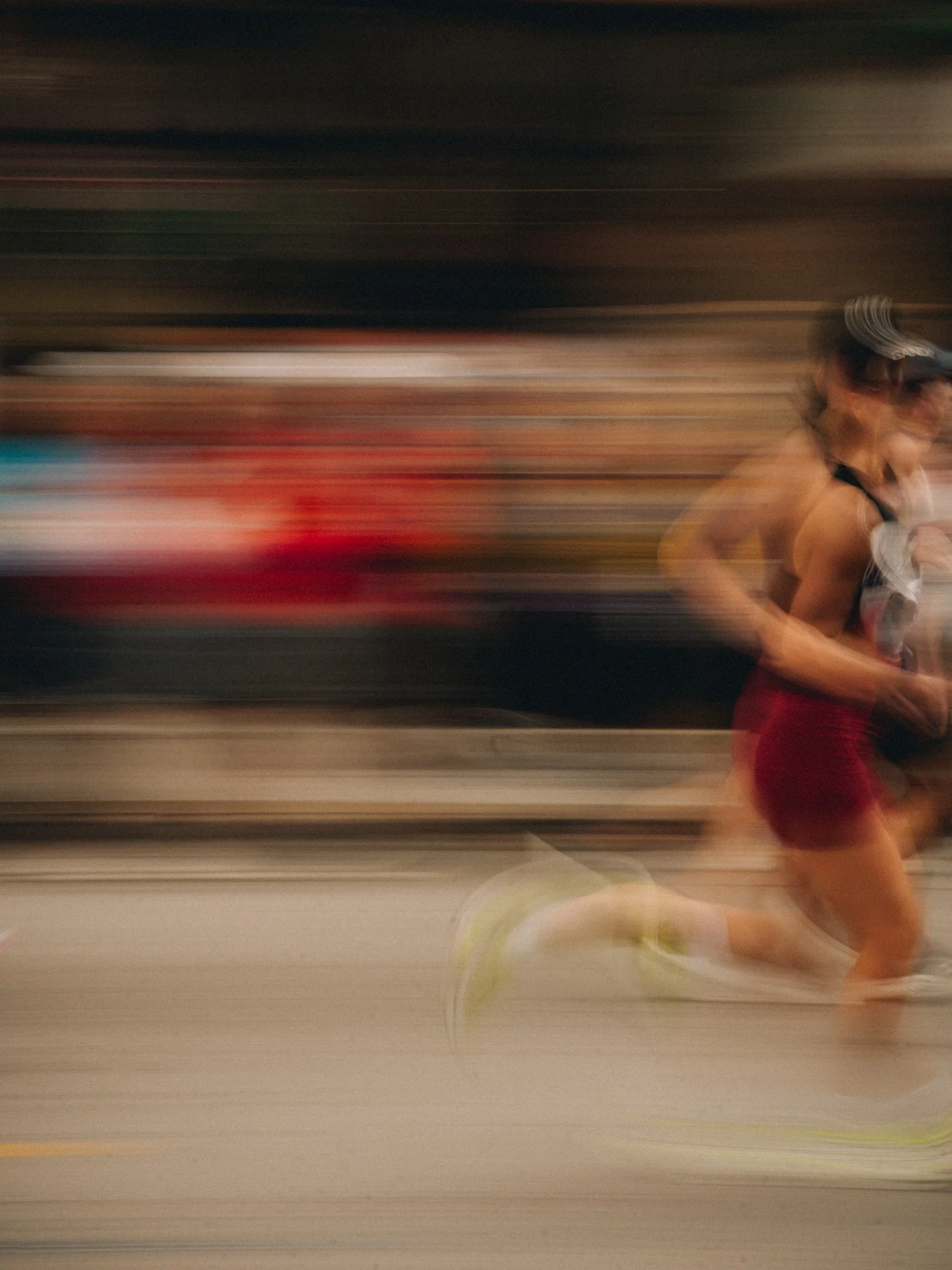 Blurry photo of a woman running on a track, wearing a sports bra and shorts, with motion blur indicating speed.