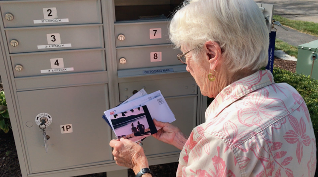 A senior collecting Smile Carrier letters from an outdoor mailbox.