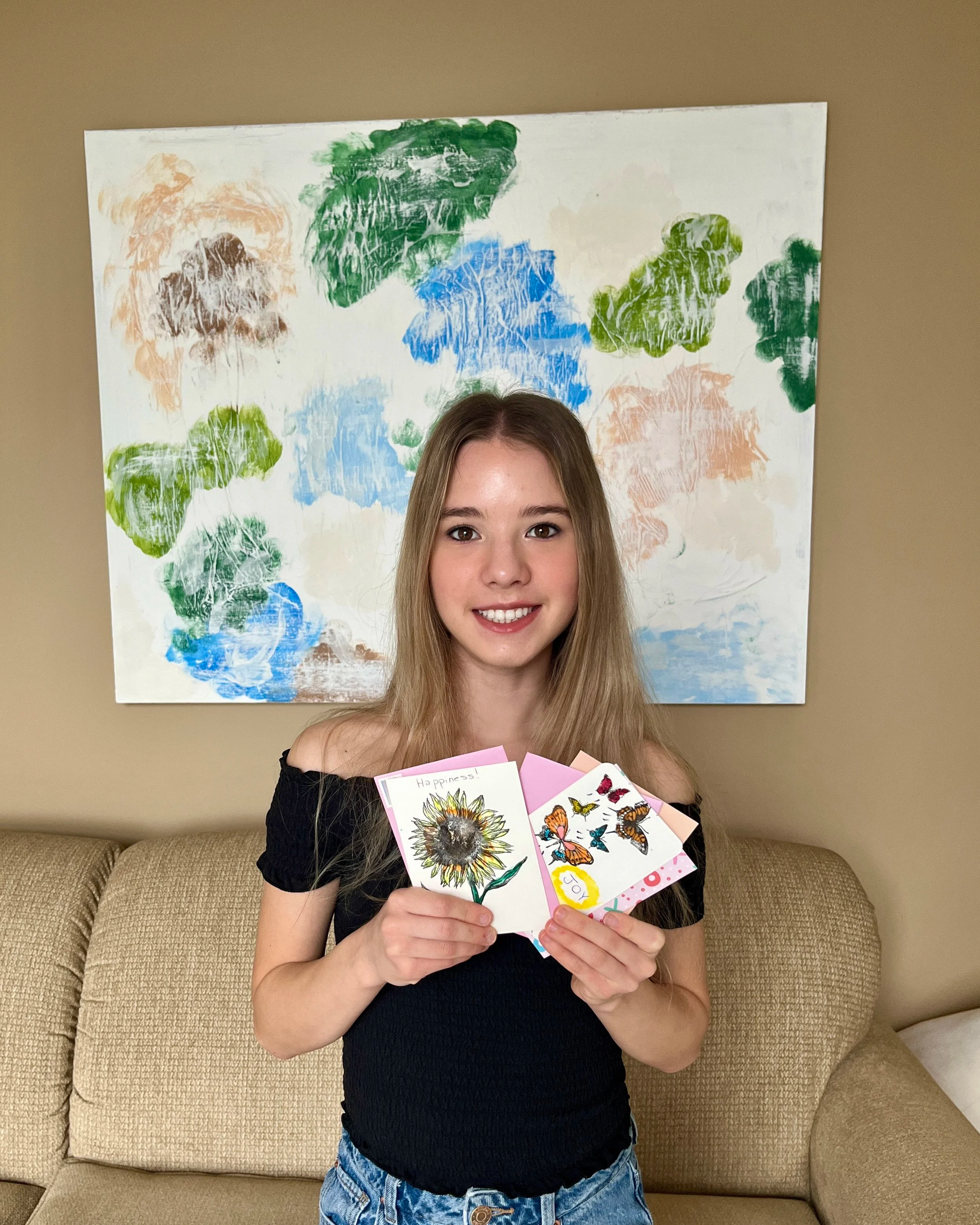 Melania, manager of Smile Carrier, smiling while holding handmade cards.