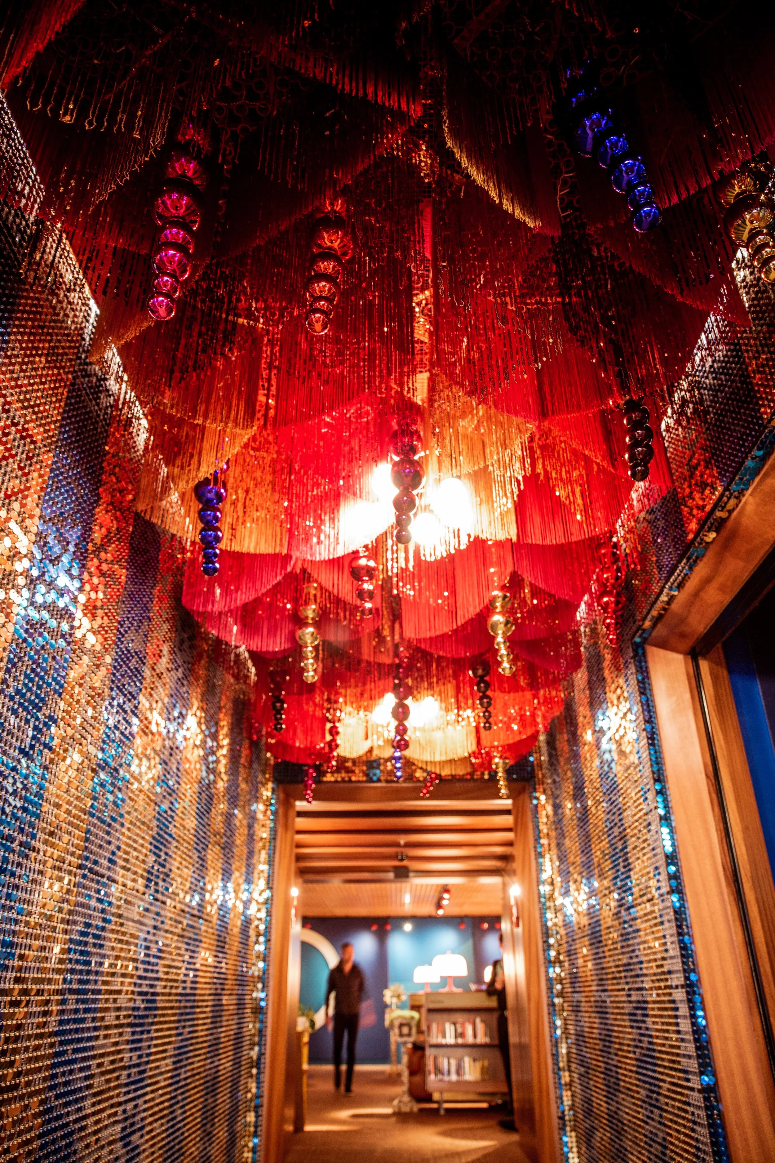 Decorative interior hallway with red fabric hanging ceiling installation, LED light fixtures, and mirrored mosaic wall panels.