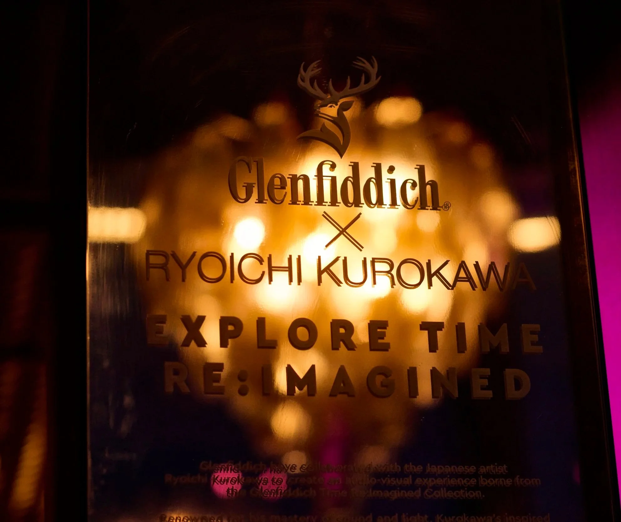 Golden-colored sign with a deer logo above the text "Glenfiddich" and additional text about an exploration experience.