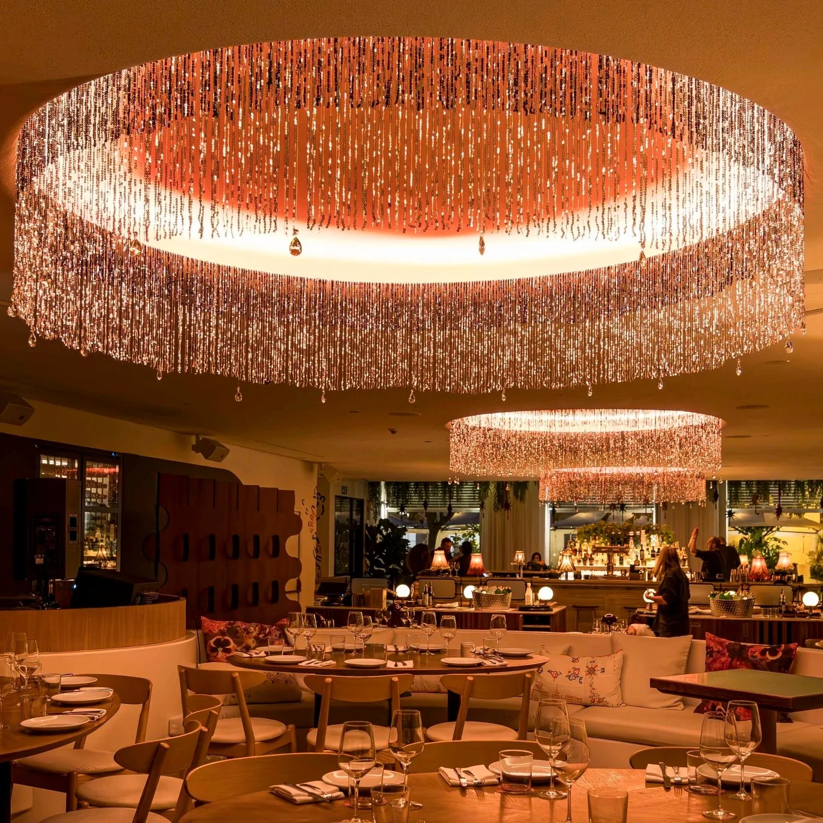 An indoor restaurant or lounge area with large, elaborate chandelier lights hanging from the ceiling.