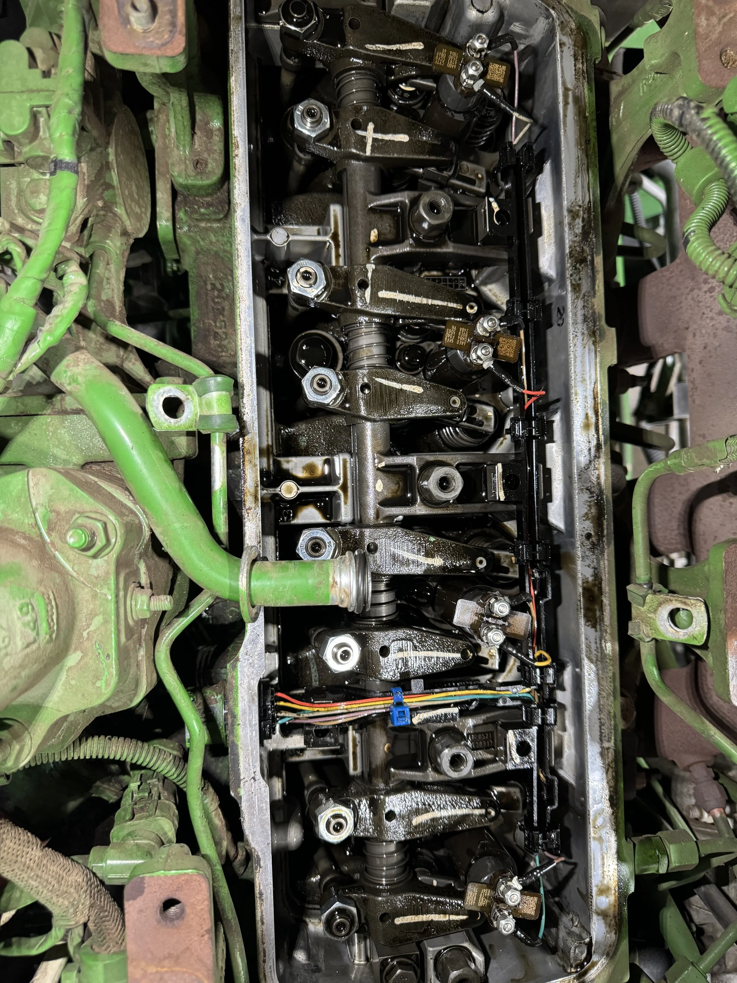 Engine cylinder head with visible internal components, including valves, springs, and rocker arms in a green engine block.
