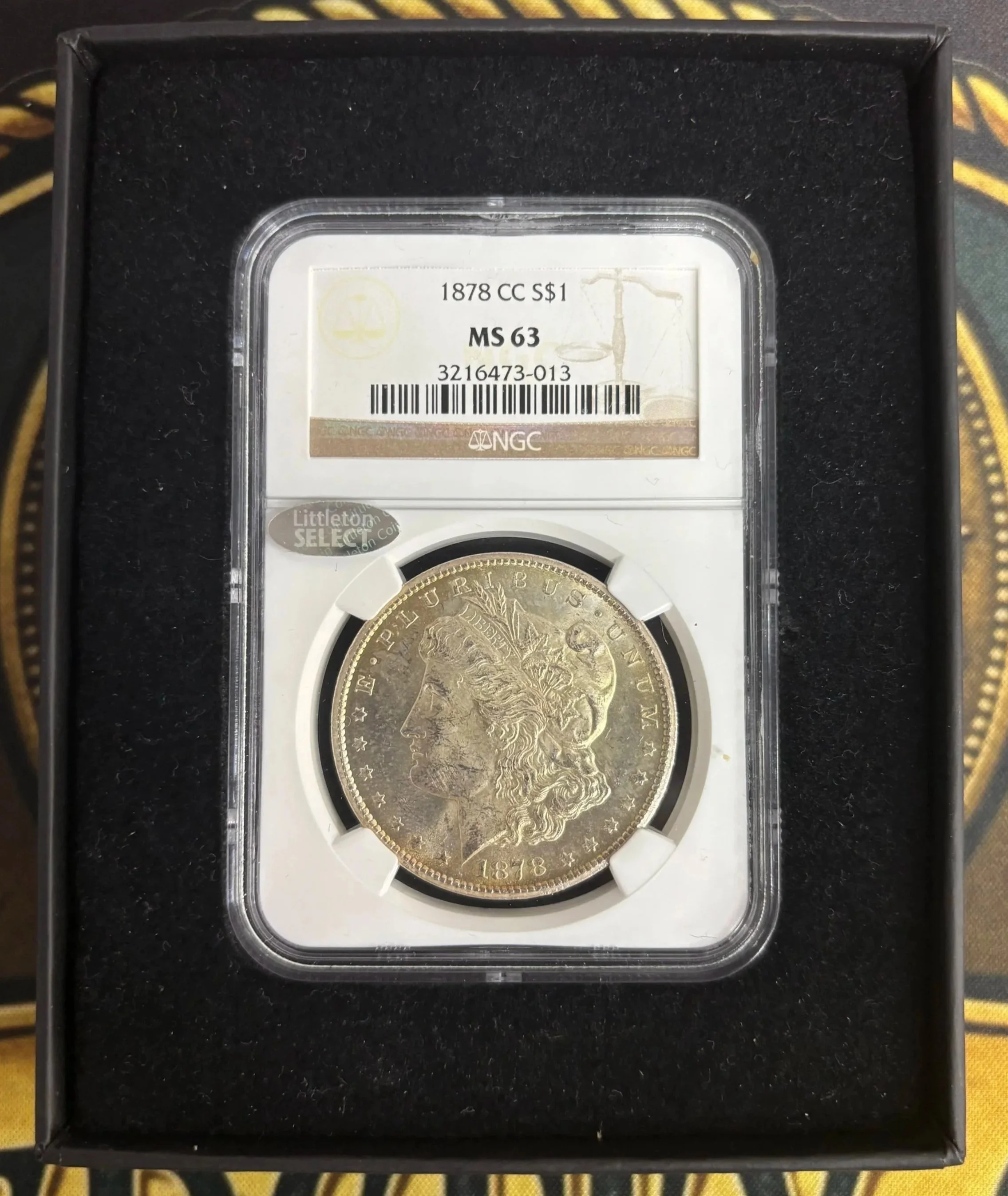 A 1878 Morgan silver dollar coin inside a clear plastic holder in a black display case.