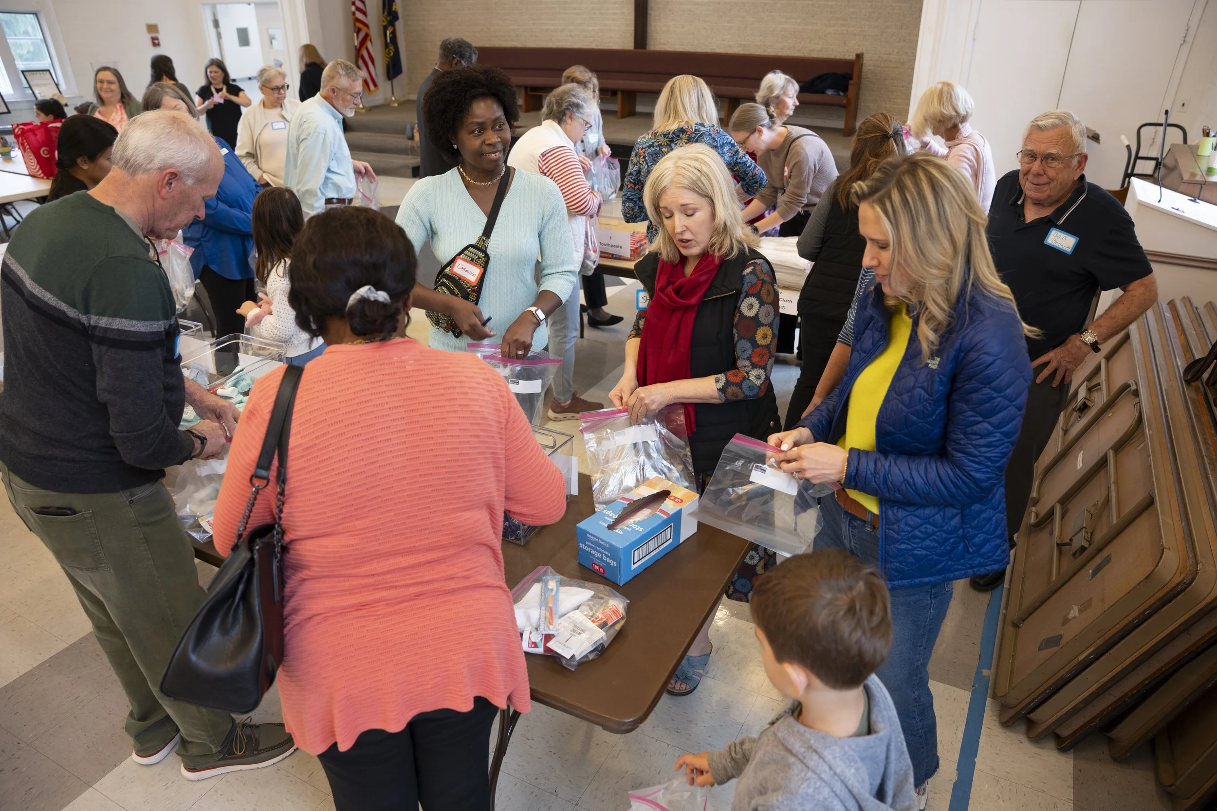 A group of volunteers packing personal care items into plastic bags for a homeless shelter.