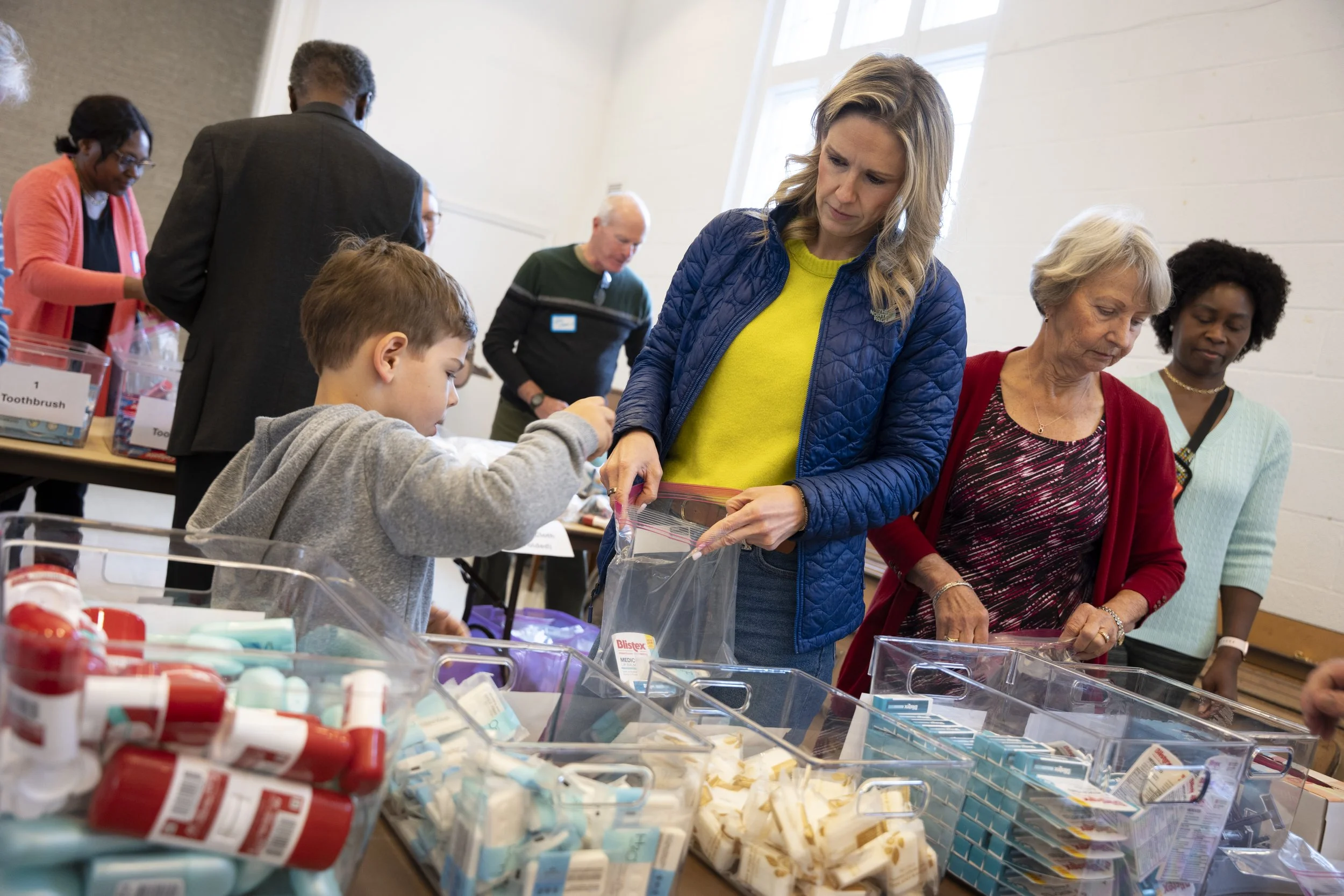 People shopping for medical supplies at a donation event, with various medical products like bandages and ointments on display.