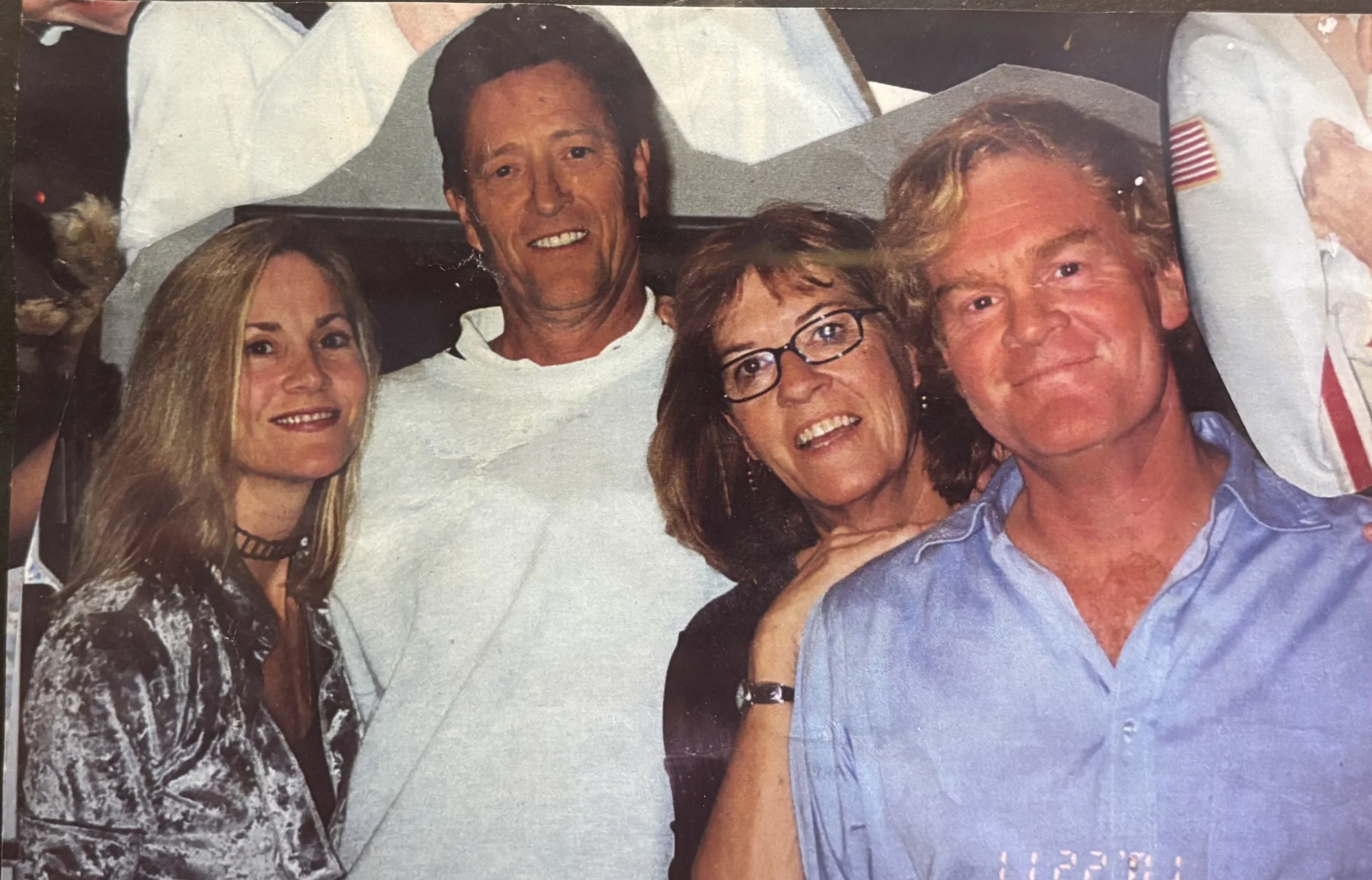 A group of five people, three women and two men, smiling closely together in a casual setting