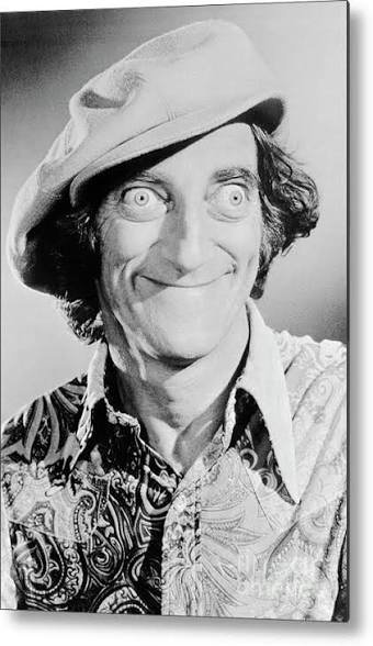 A black-and-white photo of a man wearing a hat, with a big smile, curly hair, and a patterned shirt.
