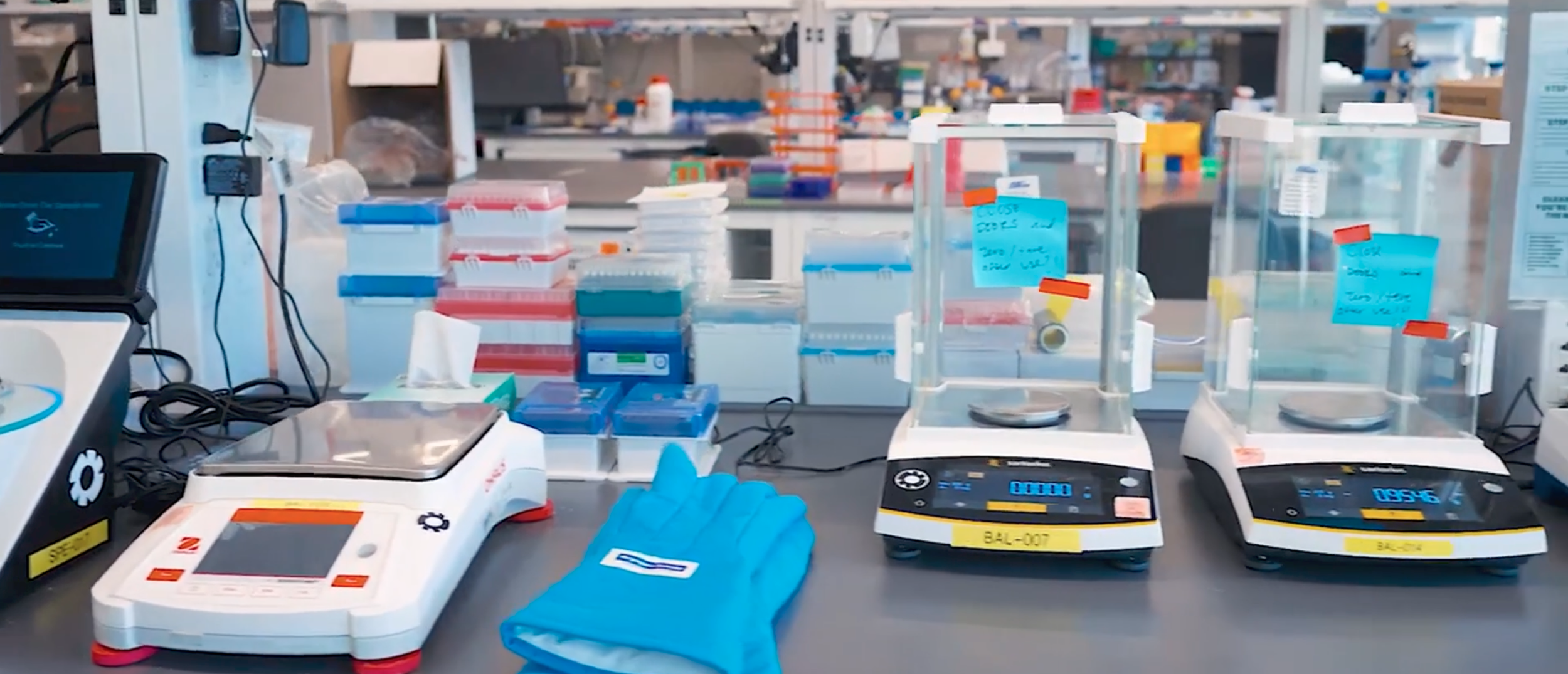 A frame from The Engine's walkthrough video - laboratory workspaces with various scales, test tube racks, and lab equipment.
