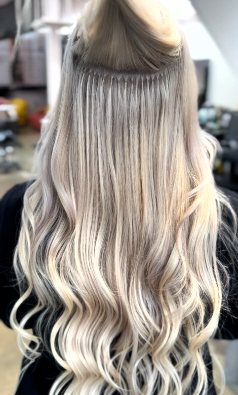 Hair extension installation with long, wavy, platinum blonde hair.