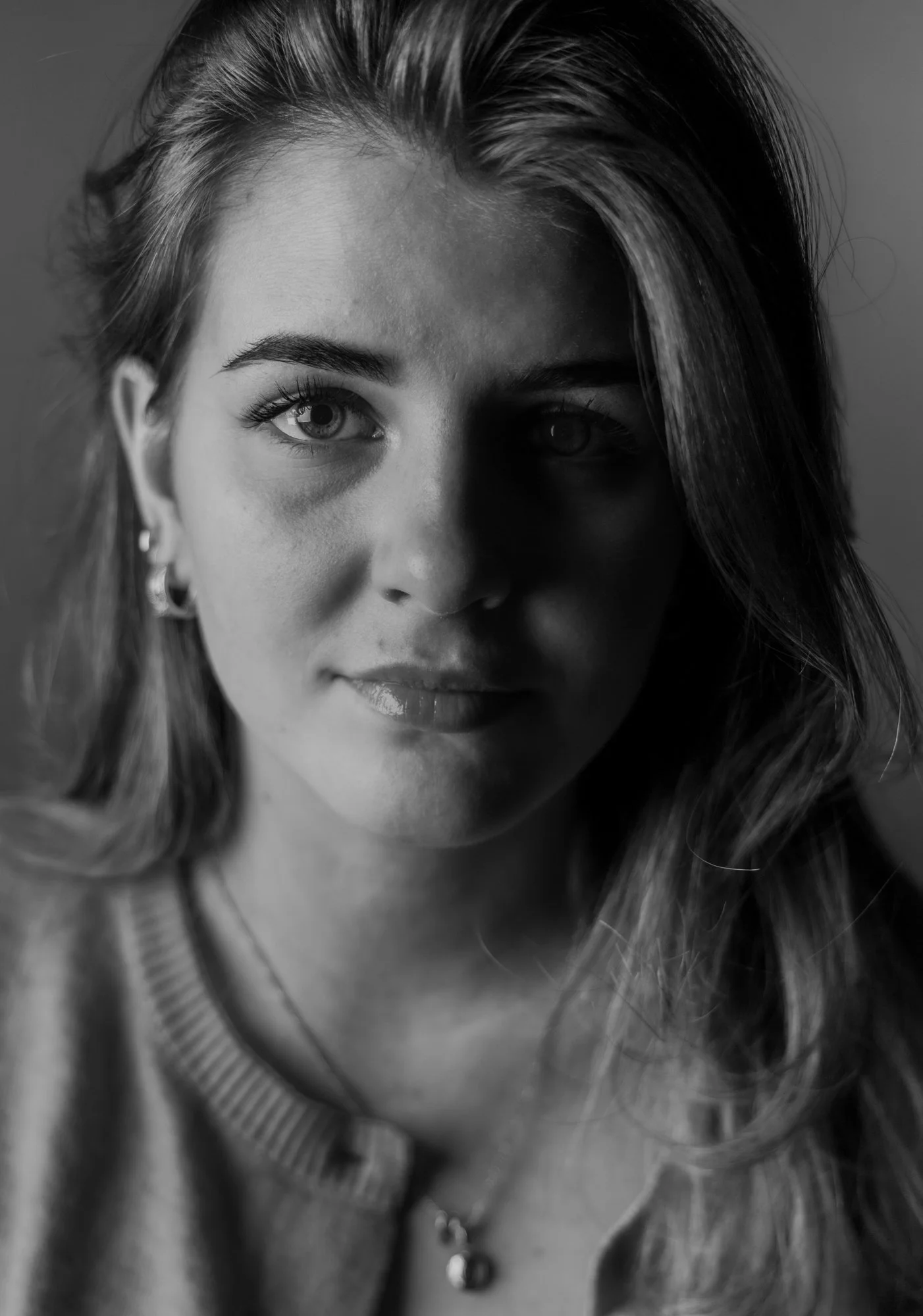 Black and white close-up of a woman with wavy hair, earrings, and a striped top.