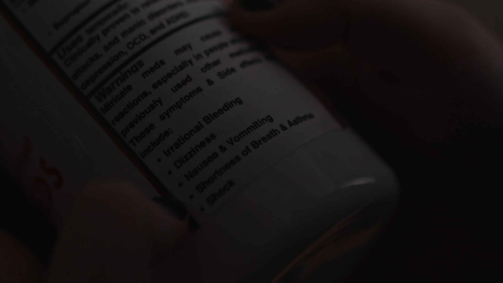 Close-up of a medicine bottle label showing safety warnings and symptoms, including dizziness, nausea, and shortness of breath.