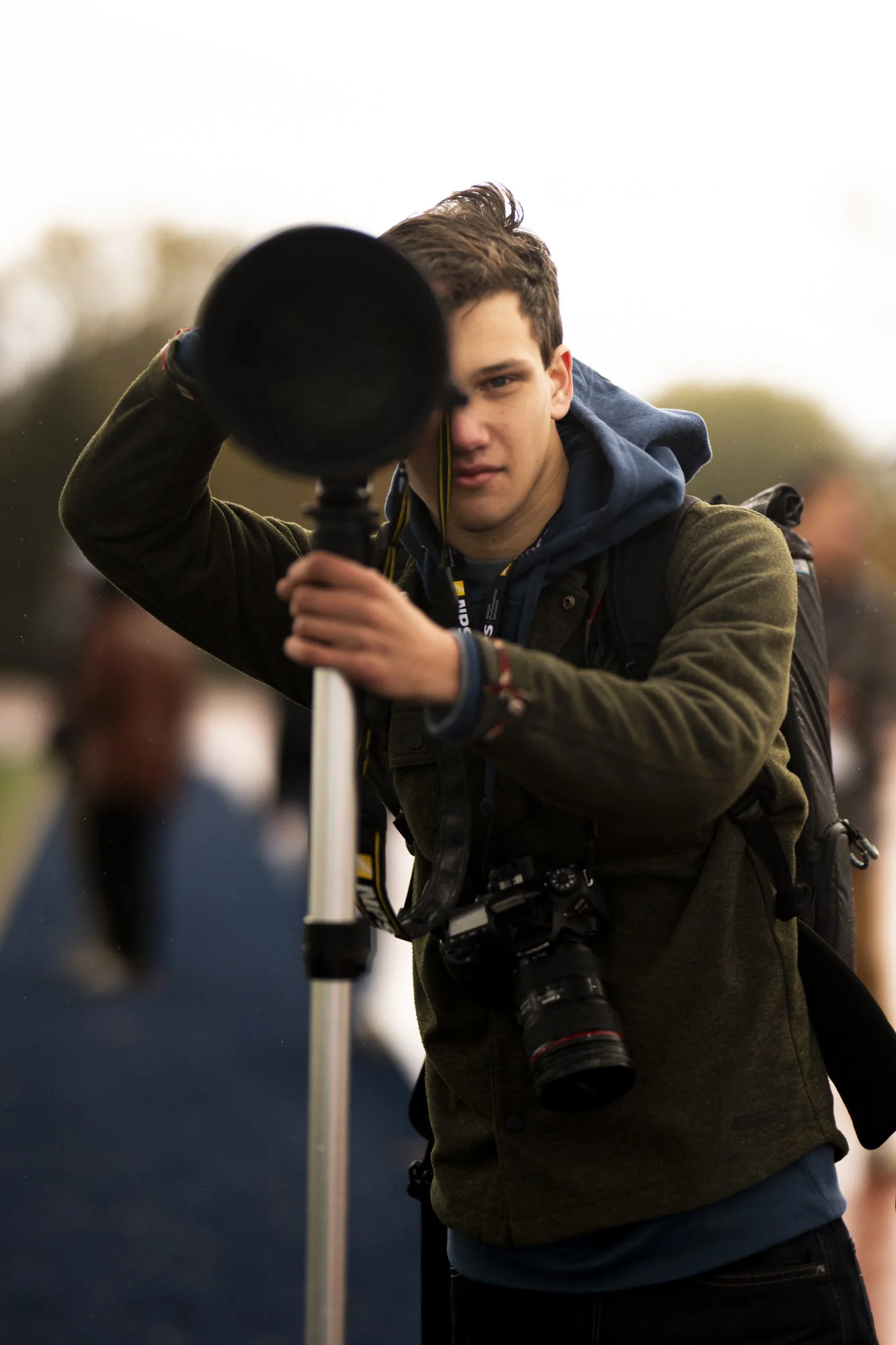 Young man with short brown hair aiming a telescope outdoors