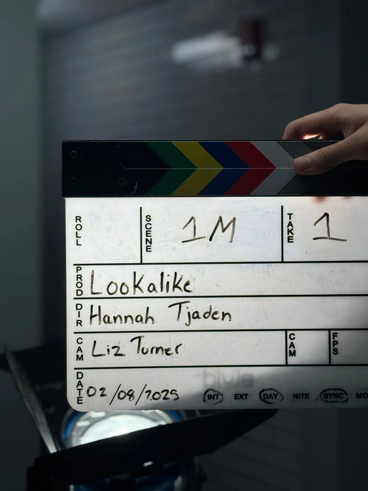 A clapperboard with handwritten scene details and a date, used in film production.