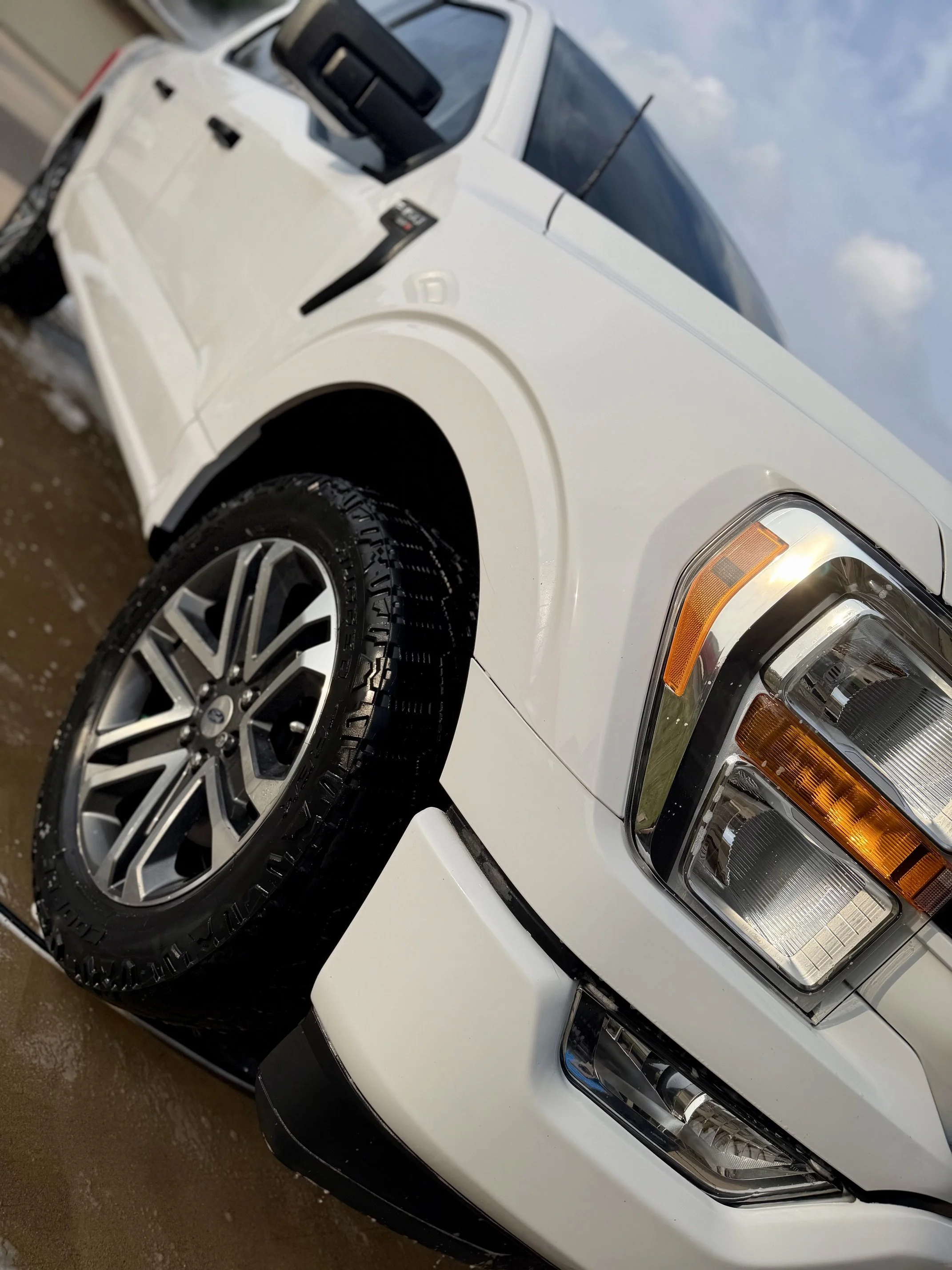 Close-up view of the front part of a white pickup truck, detailed by K&B Total Care
