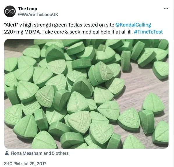 Numerous small, green, heart-shaped pills scattered on a wooden surface.
