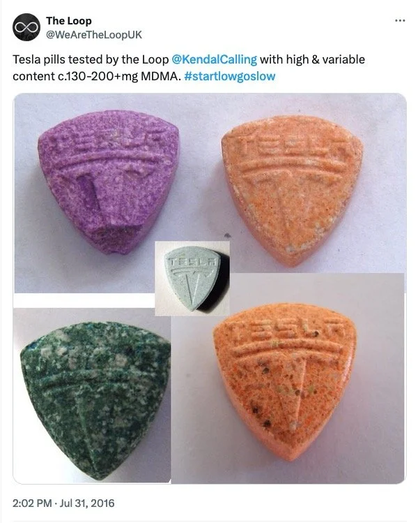 Four different colored pills shaped like Tesla logos, with the words "Tesla" on them, and an additional small white Tesla logo on a black background in the center.
