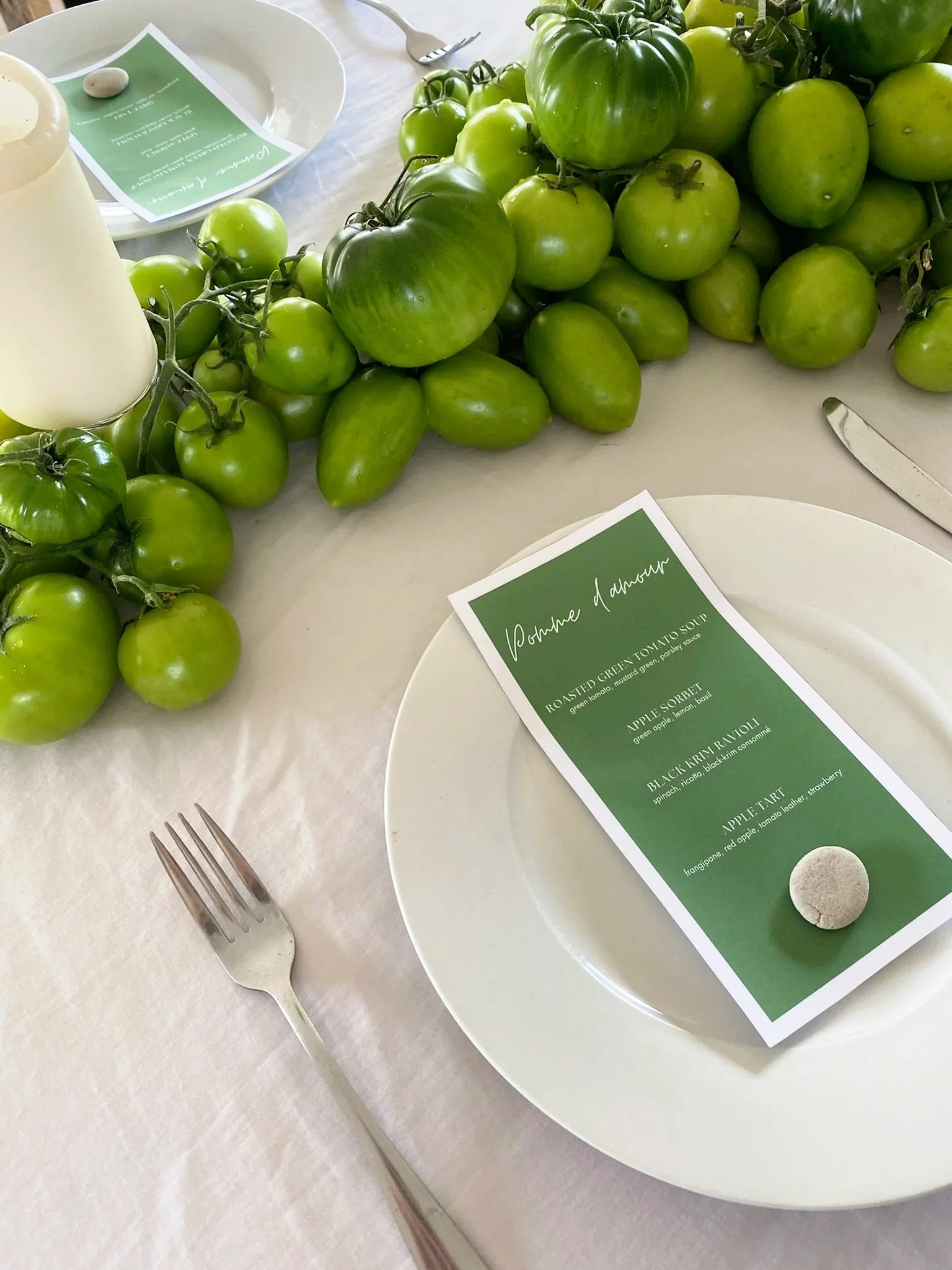 White dinning table decorated with an abundance of green tomatoes and green menus