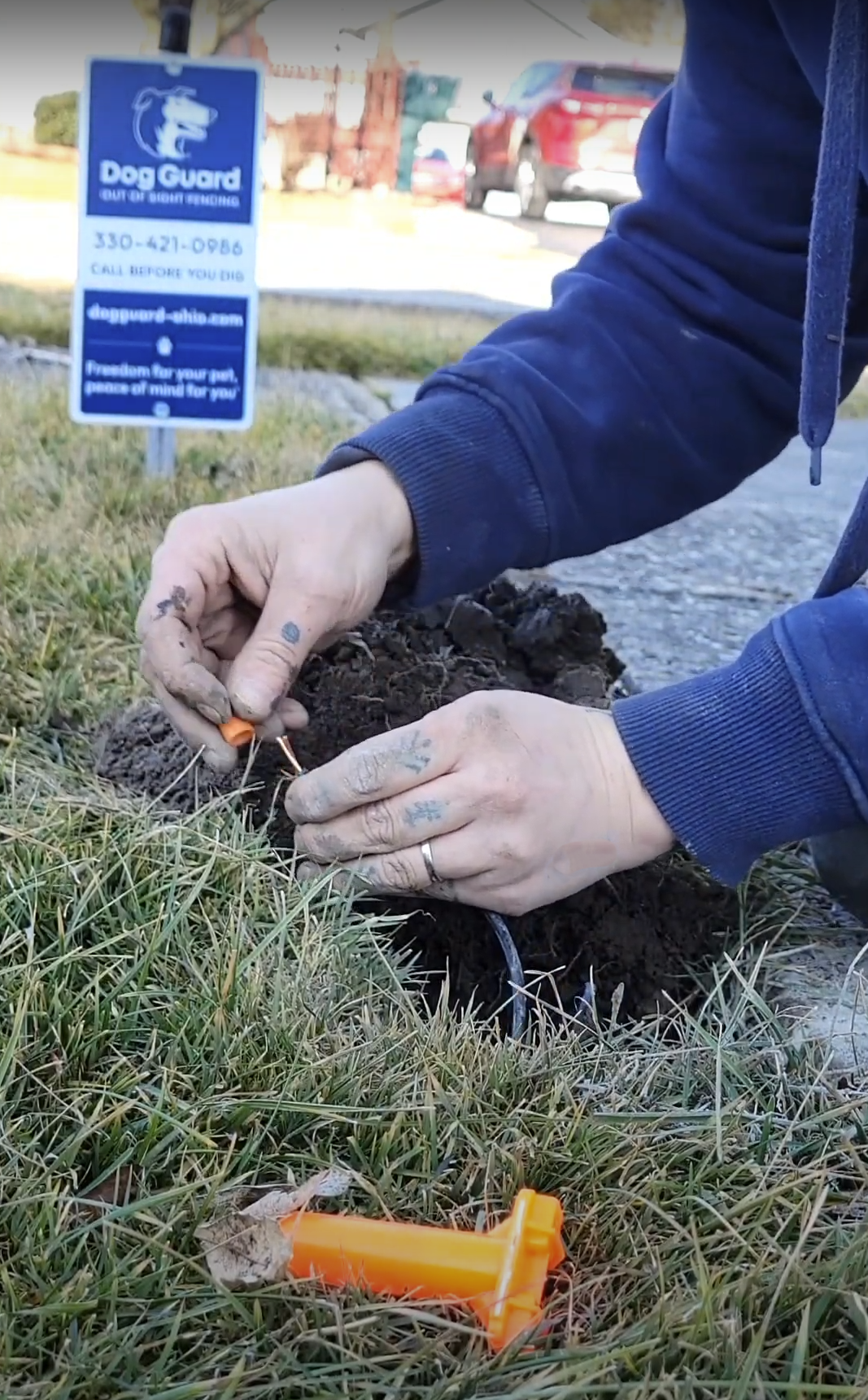 Technician repairing underground dog fence wire in grass using connectors during out of sight fencing service