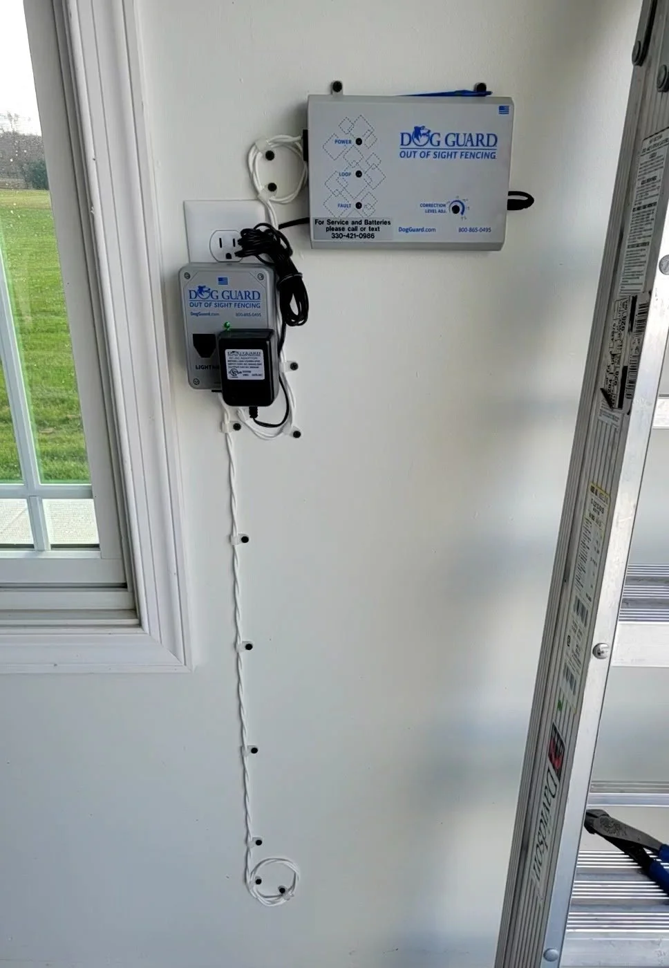 Dog Guard transmitter mounted on wall showing indicator lights used to monitor underground dog fence system status