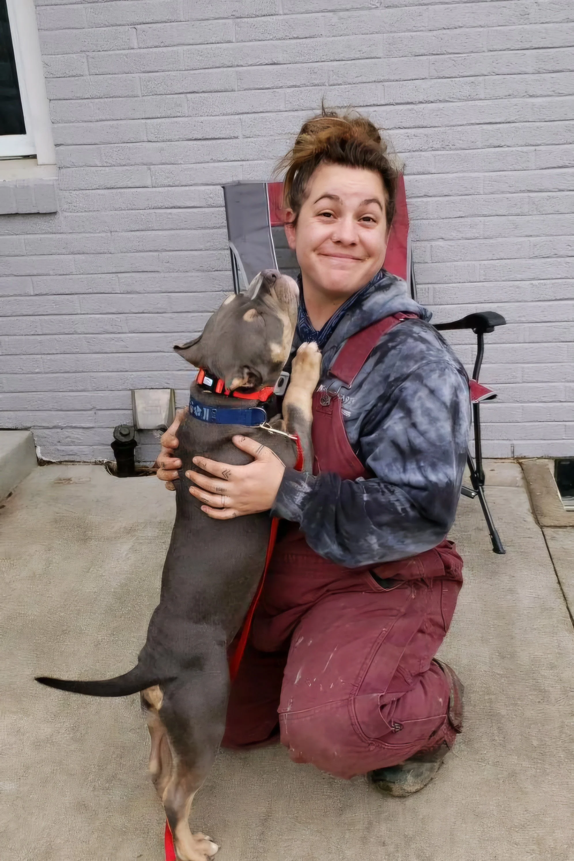 Dog licking smiling owner’s face in backyard with out of sight fencing system in place