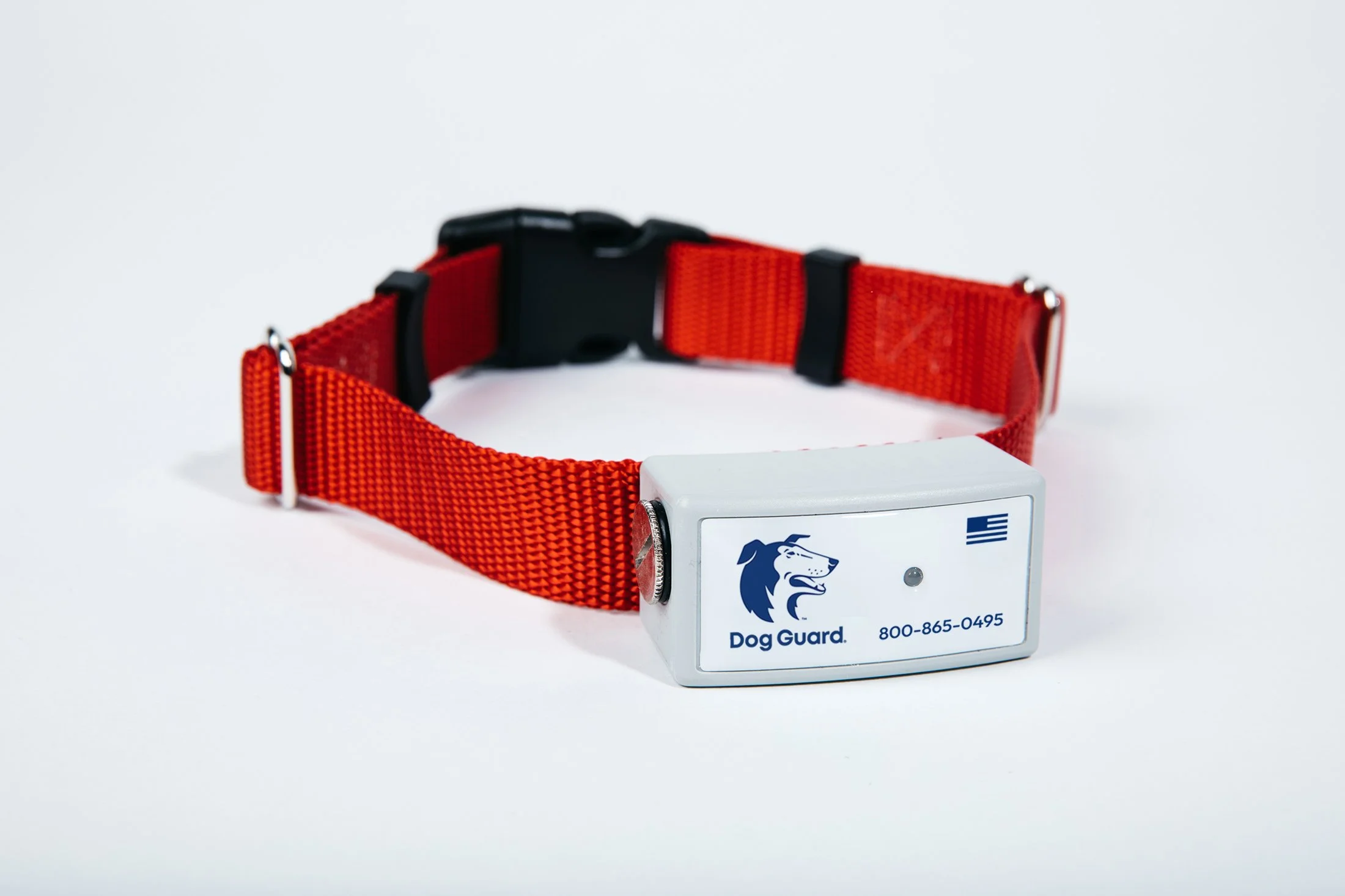 A red dog collar with a black buckle alongside a white dog GPS tracking device branded Dog Guard with a logo of a dog's head, a part of a phone number, and an American flag.