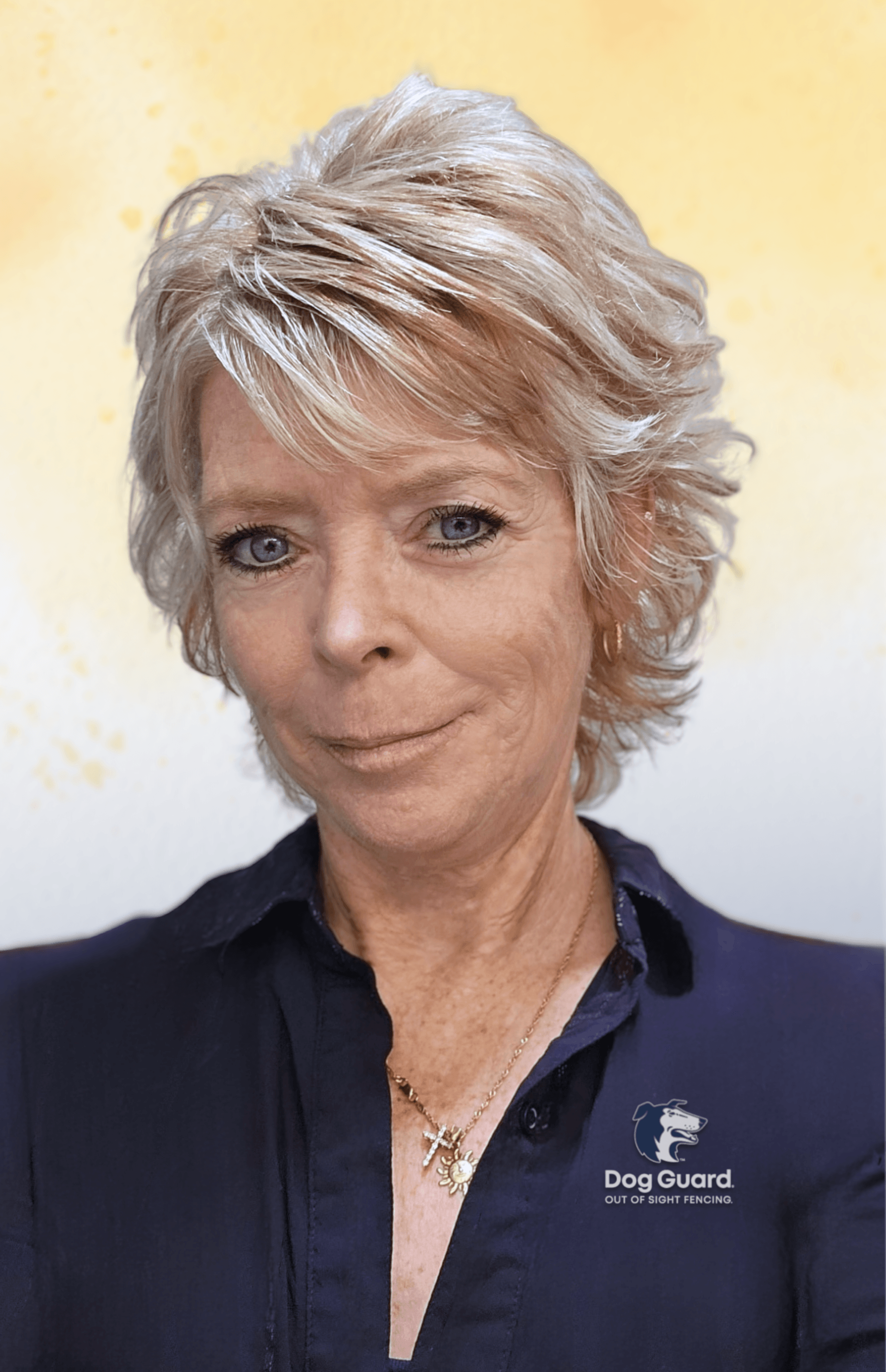 A woman with short, layered blonde hair and blue eyes is posing for a photo, wearing a dark blue collared shirt with a Dog Guard logo on it and a gold Christian cross necklace, against a yellow and white background.