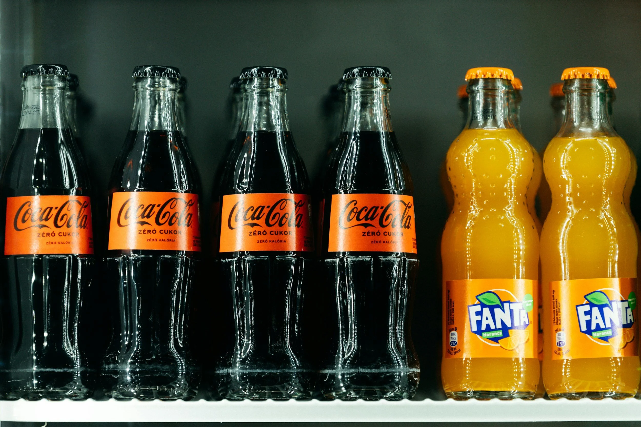 Blick auf eine Kühlschrank-Regal mit mehreren Flaschen Coca-Cola Zero Zucker und Orangensaft.