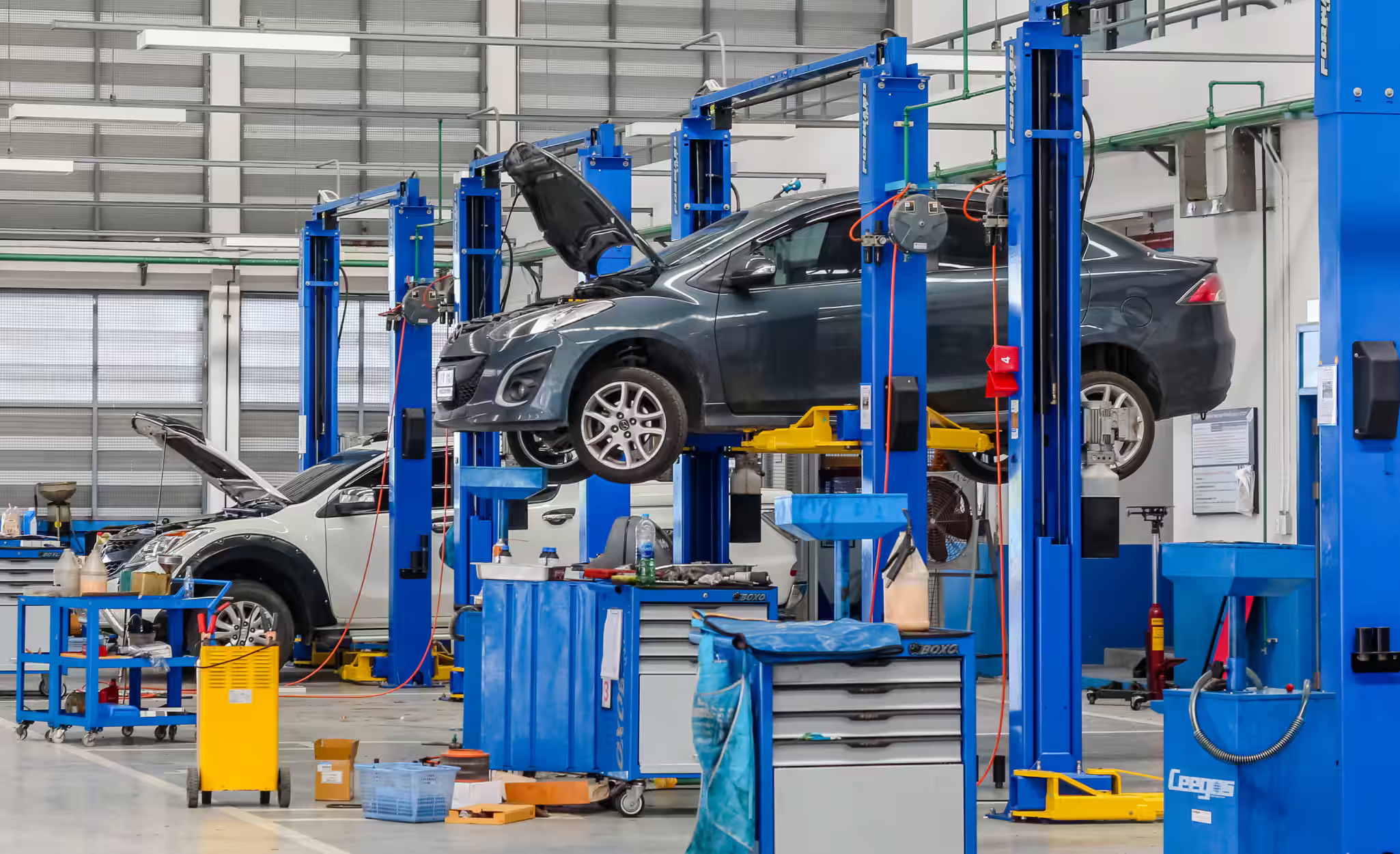 Auto repair shop with a black car on a lift, mechanic tools, and equipment.