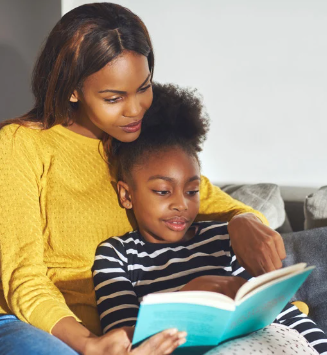 girl reading a book to her mother