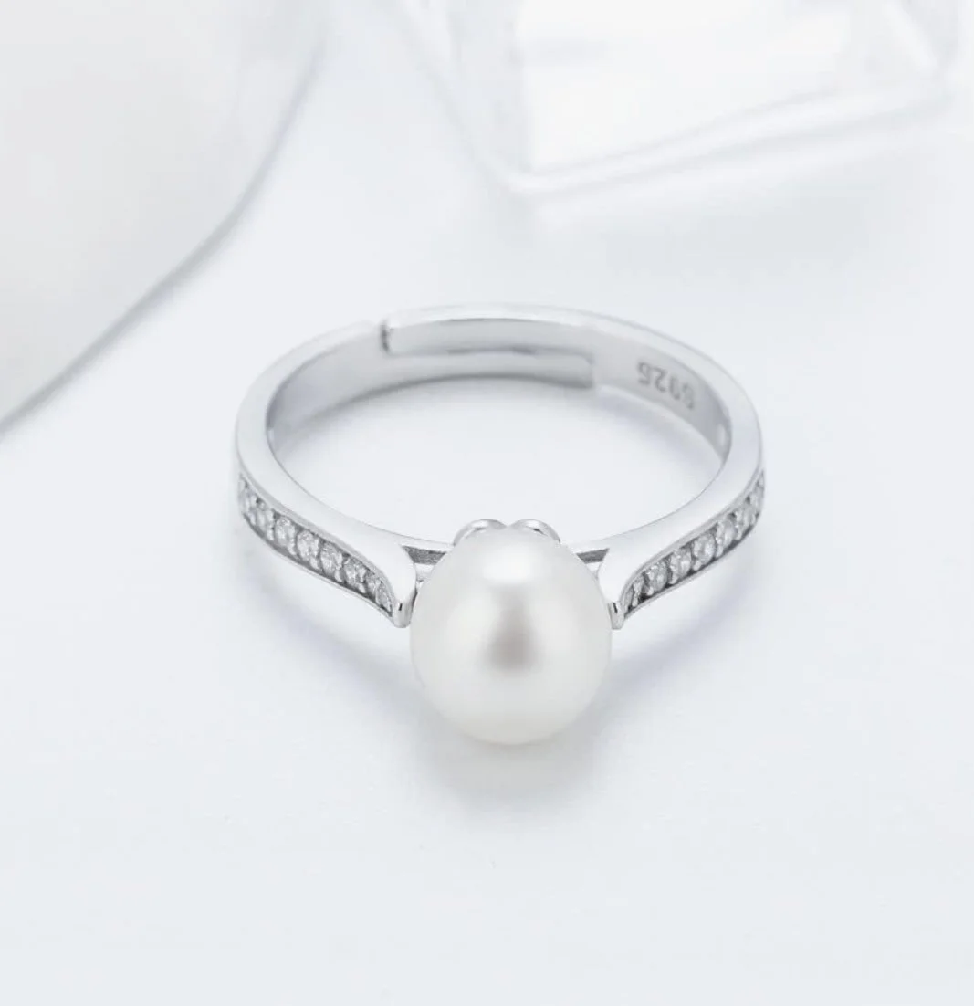 Silver ring with a large pearl and small diamonds on the band.
