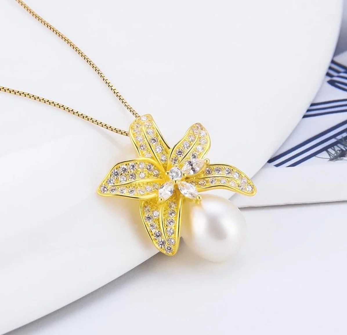 Gold necklace with a flower-shaped pendant decorated with small diamonds and a large pearl