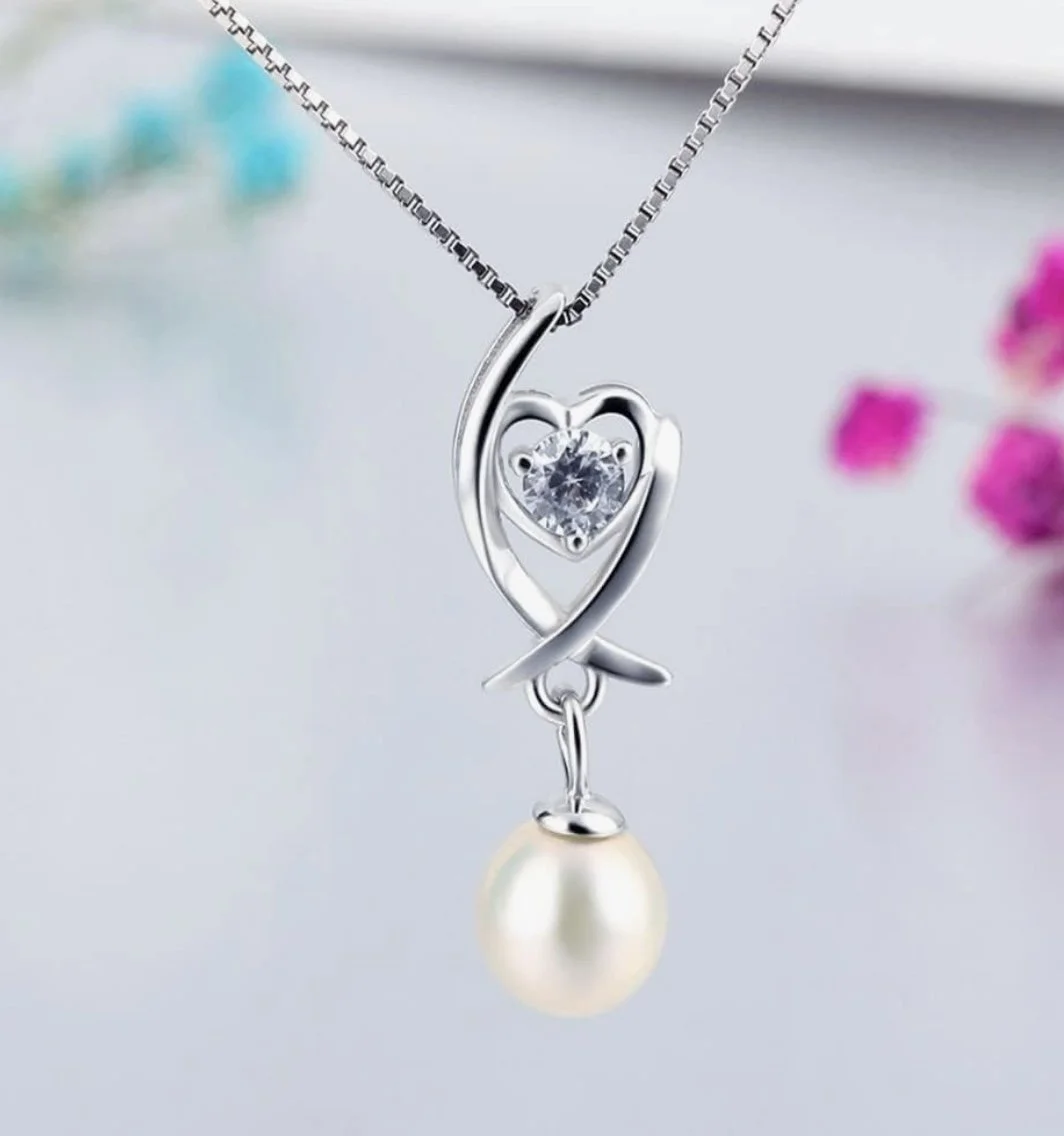 Silver necklace with a heart-shaped pendant, a central gemstone, and a dangling pearl.