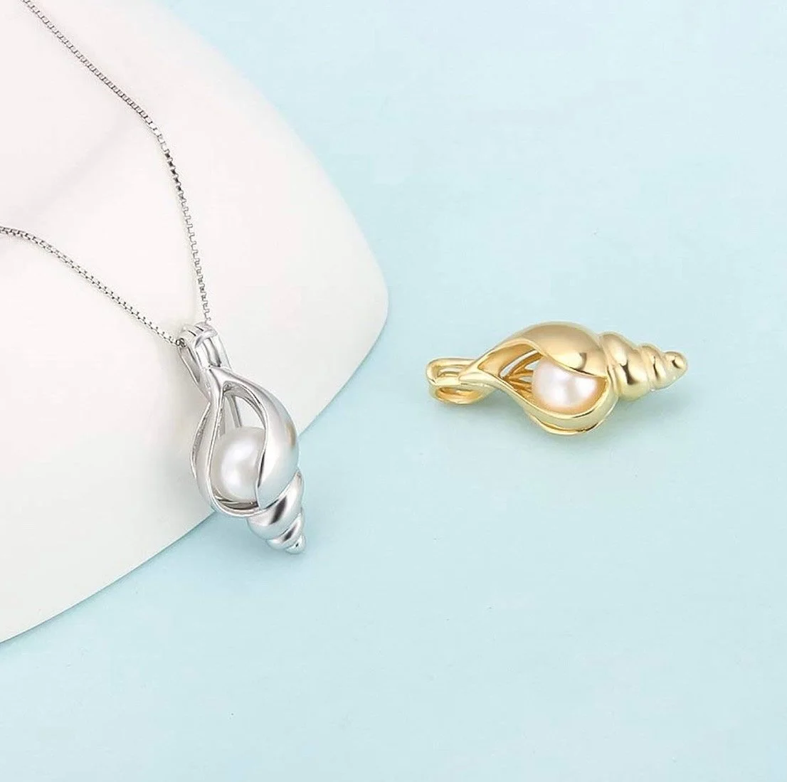 Silver and gold seashell-shaped jewelry with pearl accents on a pastel background.