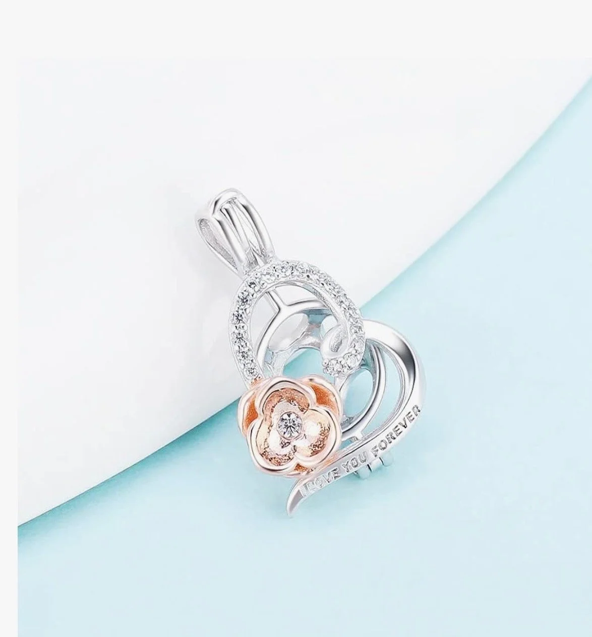 Silver pendant with a flower design, rhinestones, and an inscription reading 'LOVE YOU FOREVER' on a light blue background.