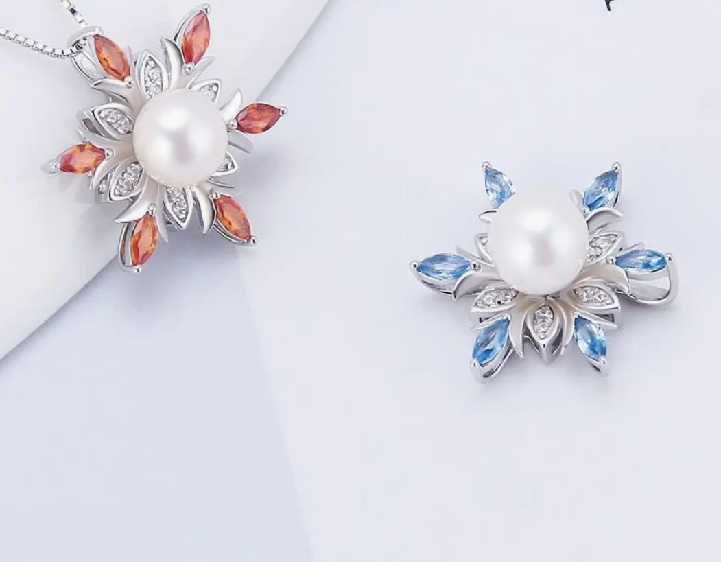 Pair of floral earrings with large pearl center, one with orange stones and the other with blue stones.