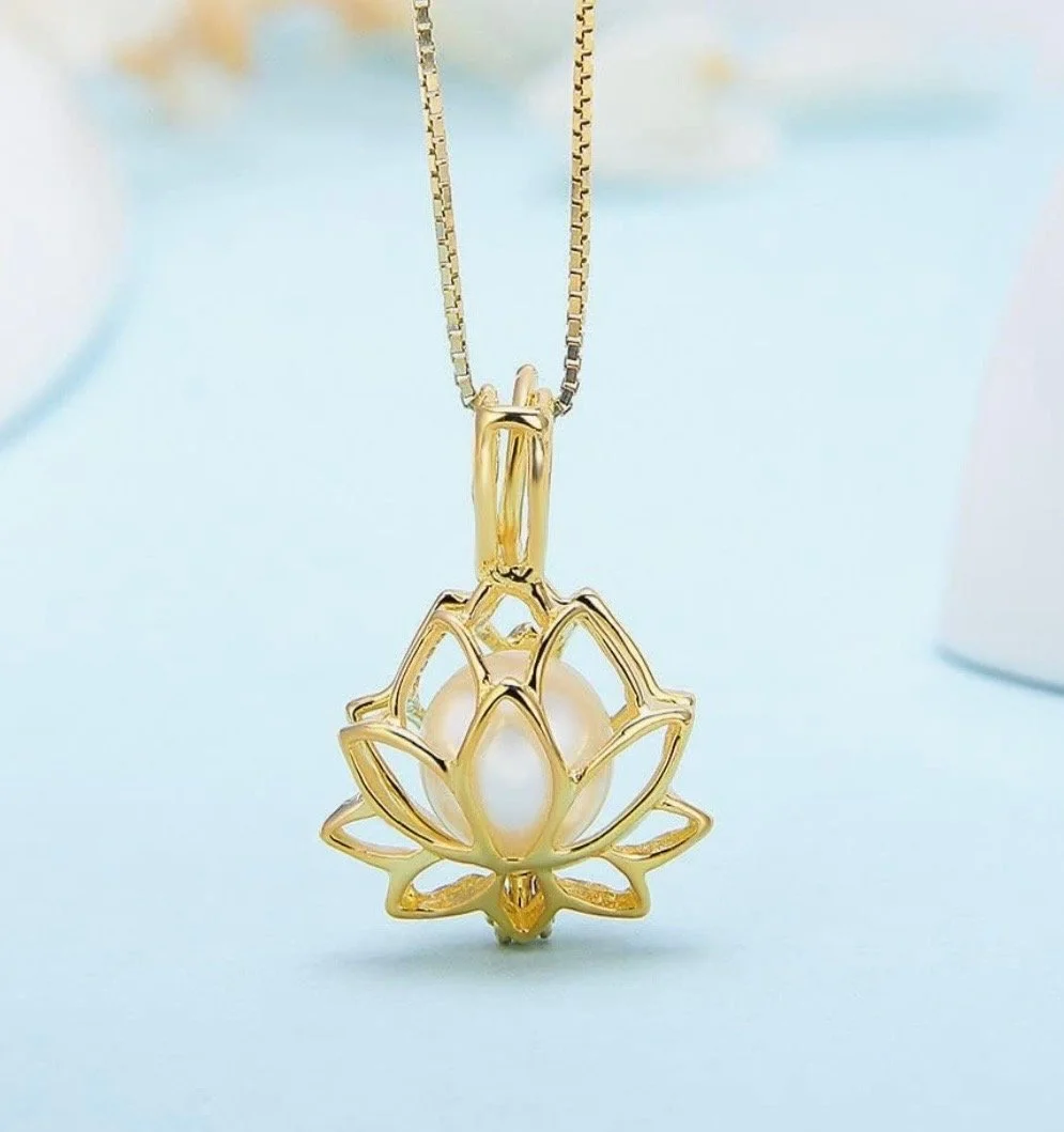 Gold pendant necklace with a white pearl inside a lotus flower-shaped frame.